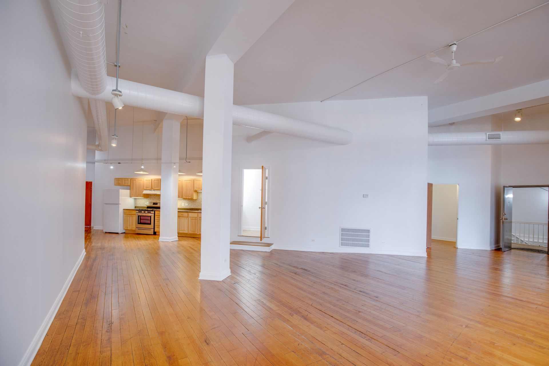 A large empty room with hardwood floors and white walls