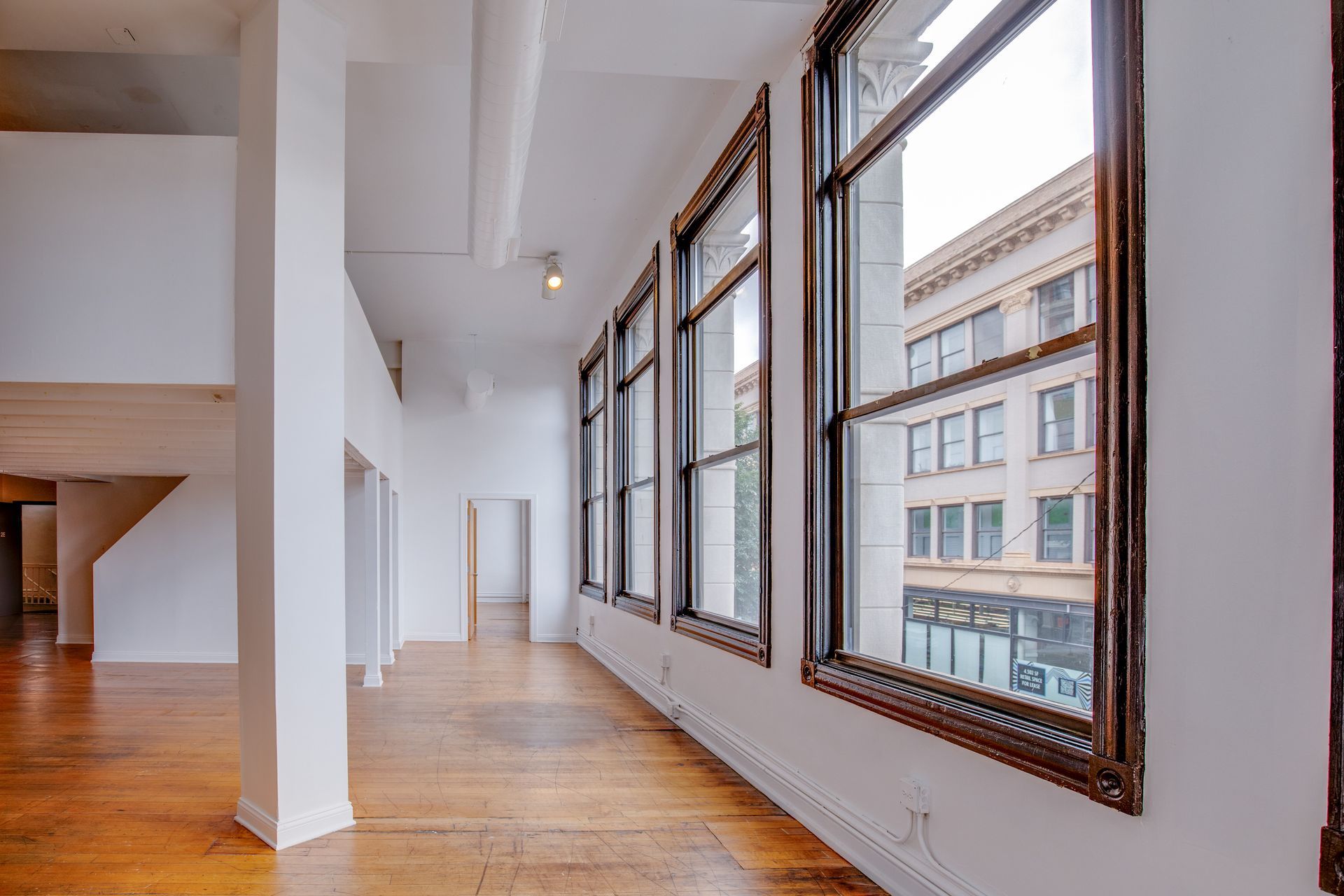A large empty room with lots of windows and wooden floors.