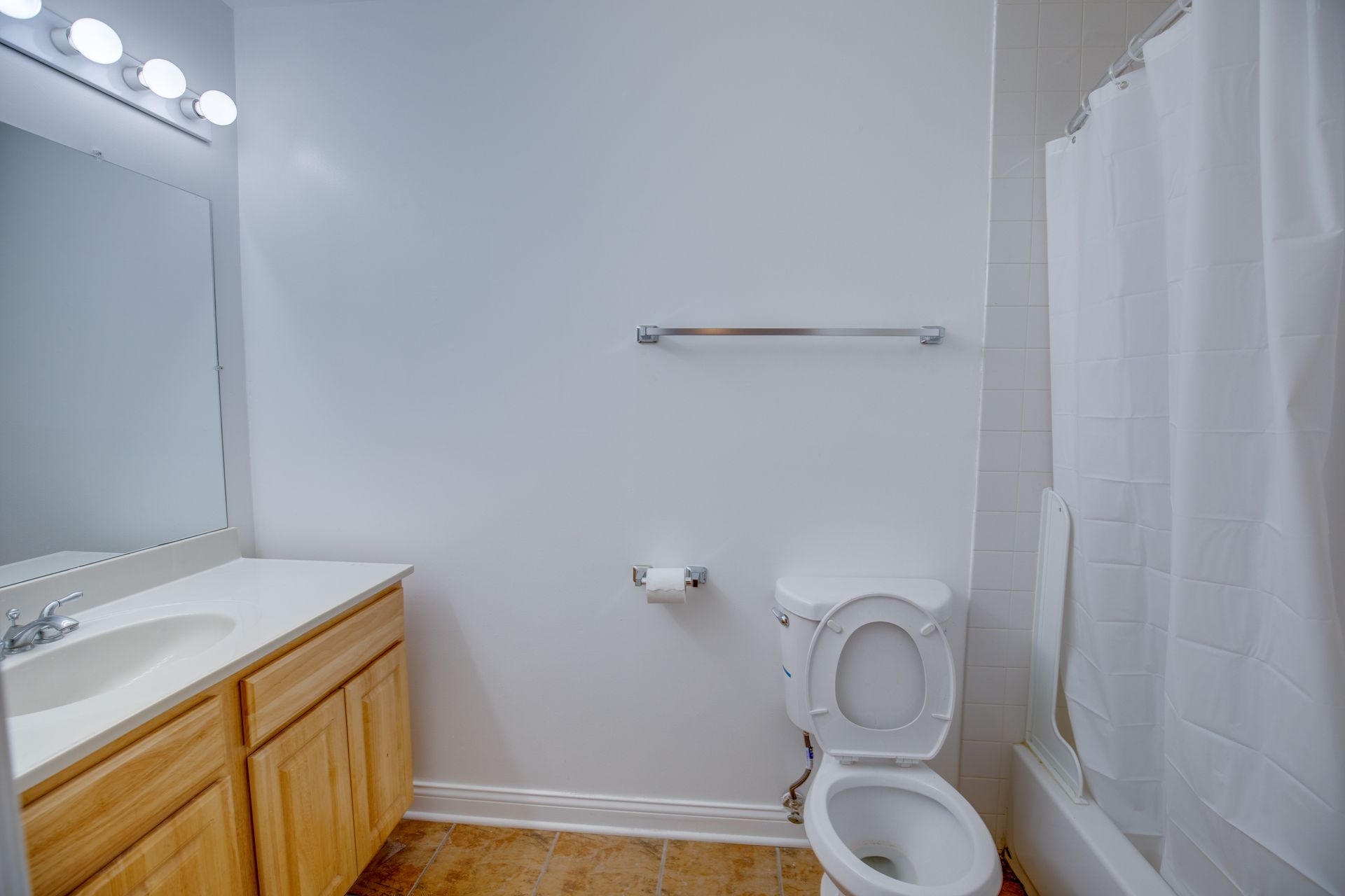 A bathroom with a toilet , sink and mirror.