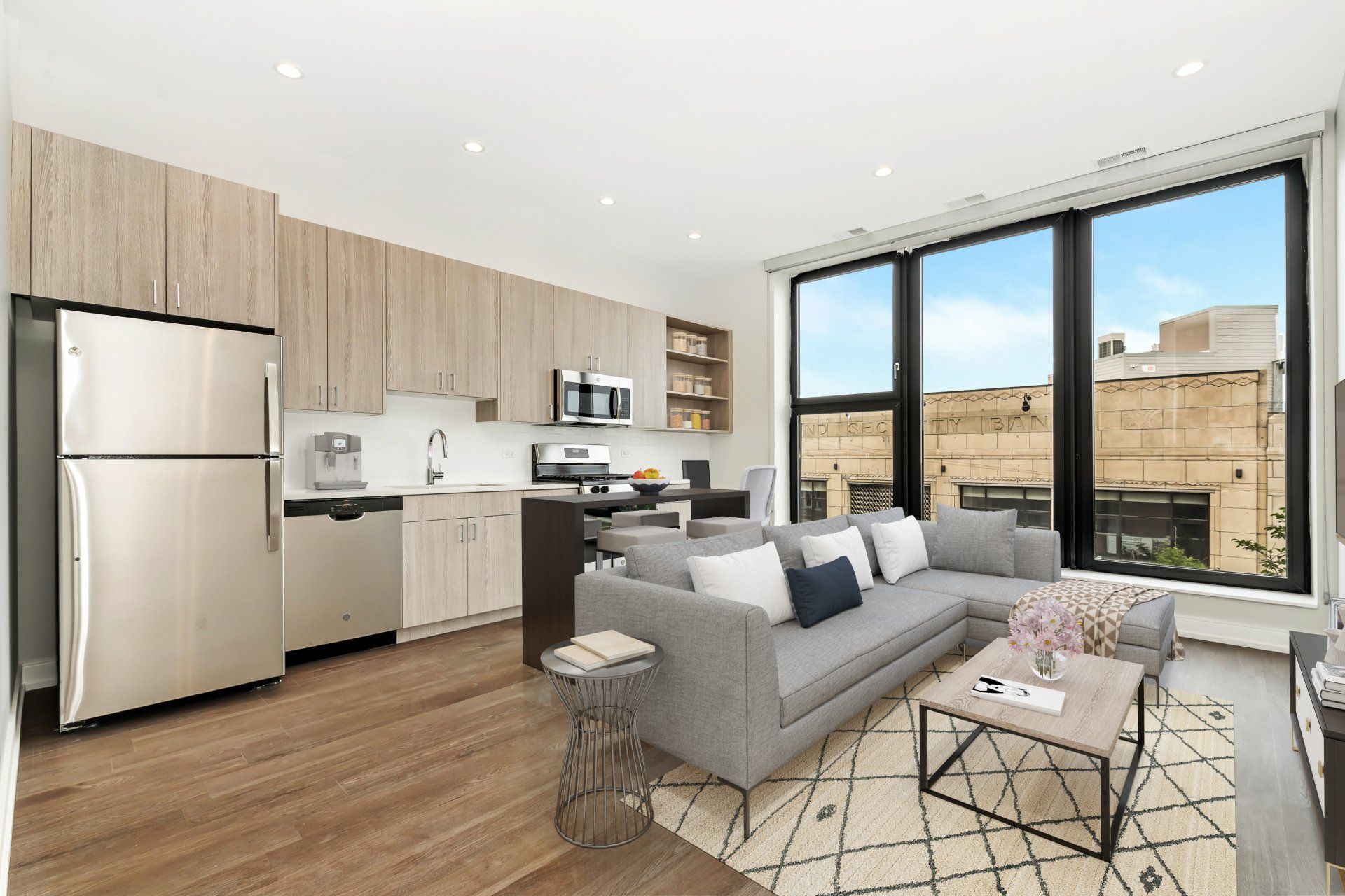 A living room with a couch , coffee table , and stainless steel refrigerator.