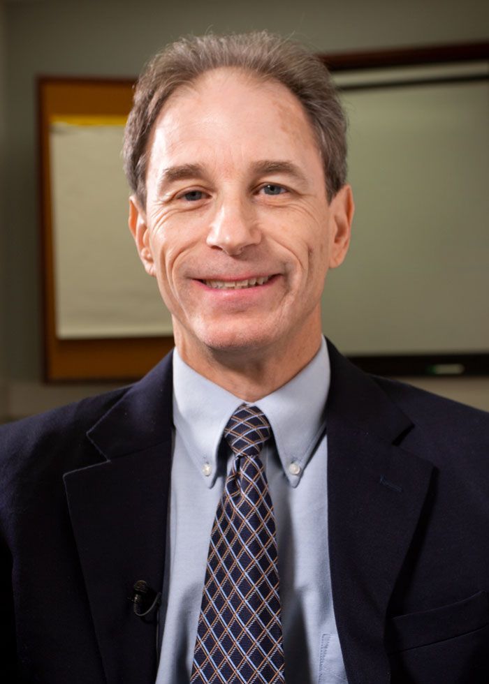 A man in a suit and tie is smiling for the camera