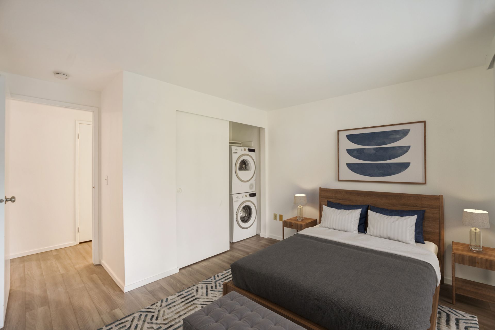 A bedroom with a large bed and a washer and dryer.