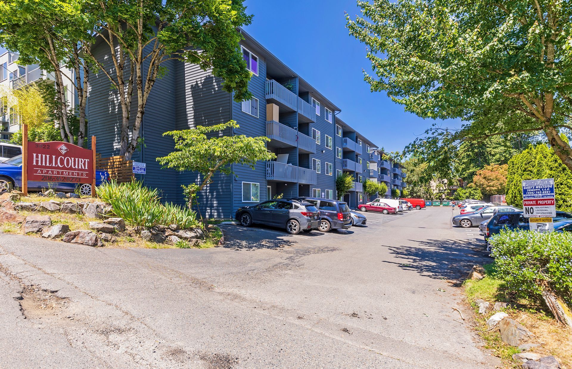 A large apartment building with a lot of cars parked in front of it.