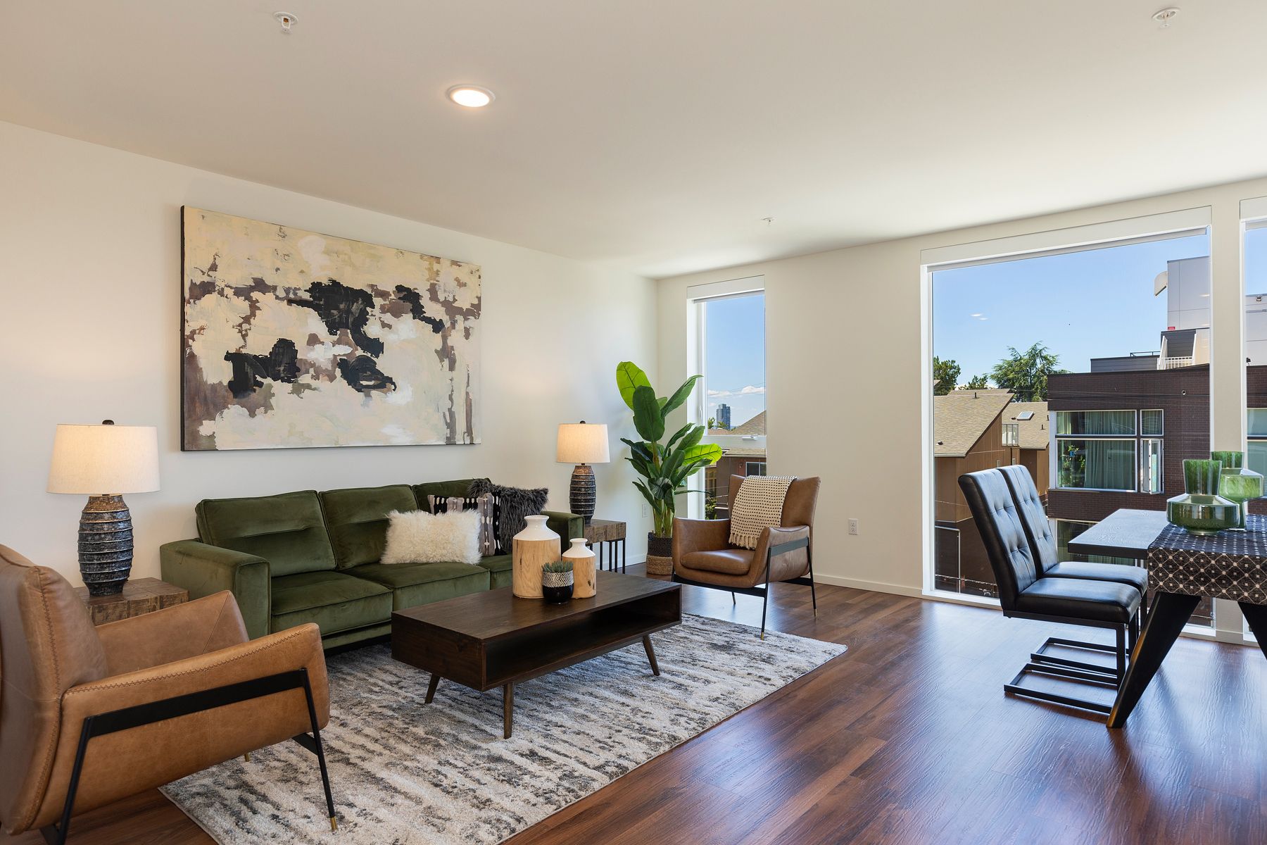 A living room with a green couch , two chairs , a coffee table , and a large window.