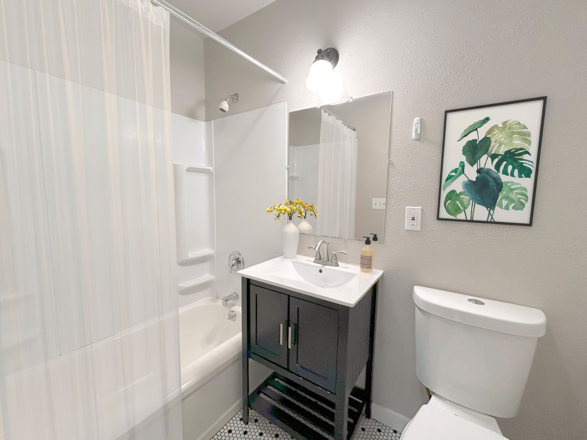 A bathroom with a sink , toilet , tub and mirror.