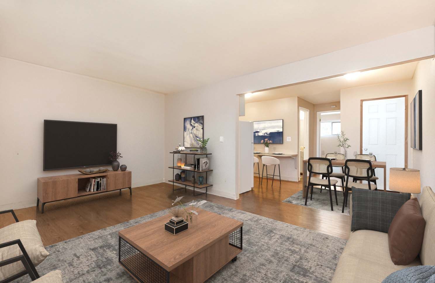 A living room with a couch , coffee table , television and dining room.