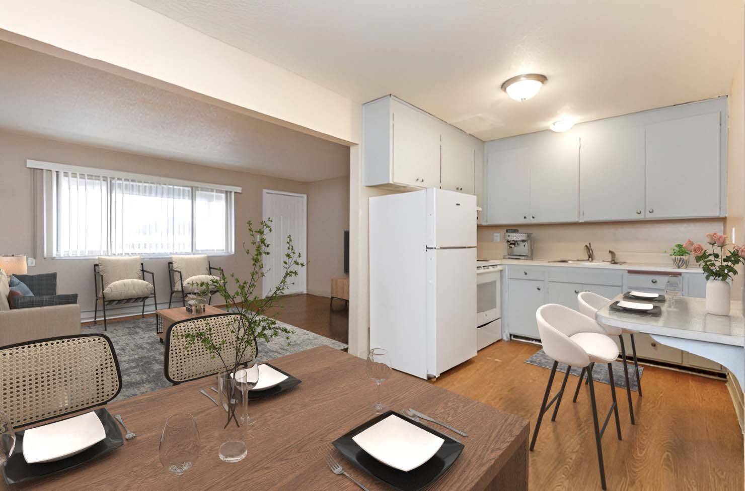 A living room with a dining table and chairs and a kitchen with a refrigerator.