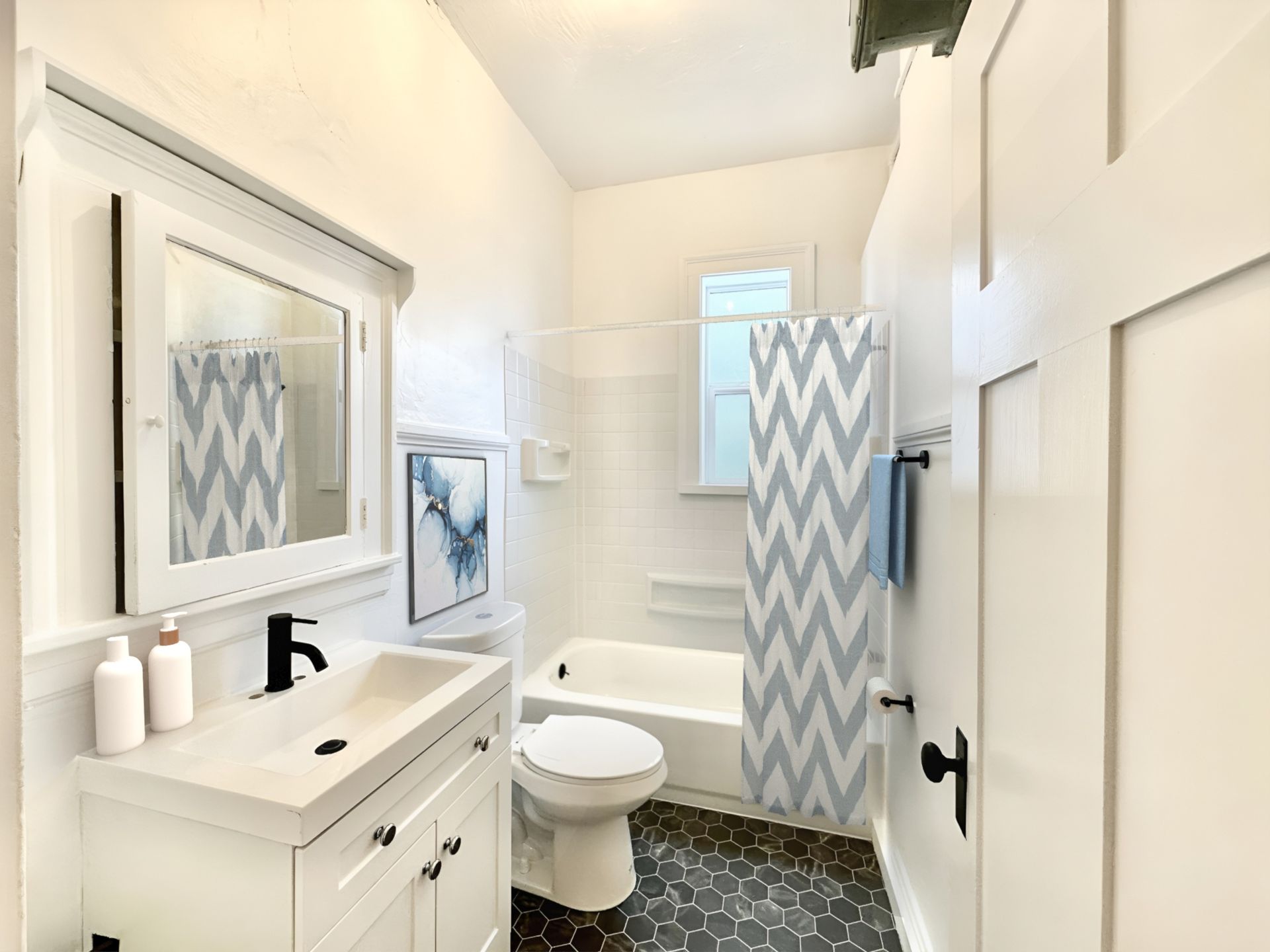 A bathroom with a toilet , sink , mirror and shower curtain.