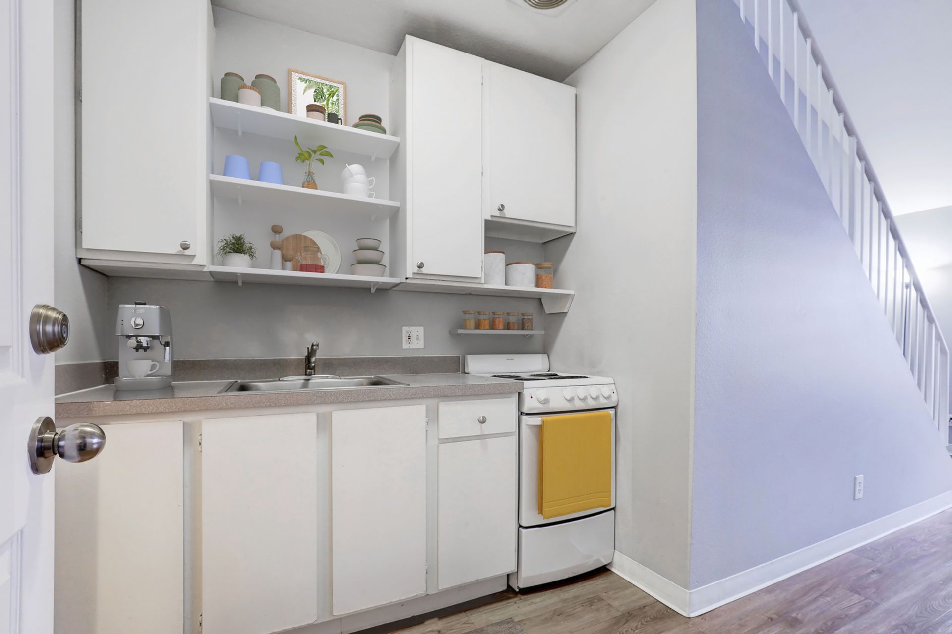 A small kitchen with white cabinets and a yellow stove.