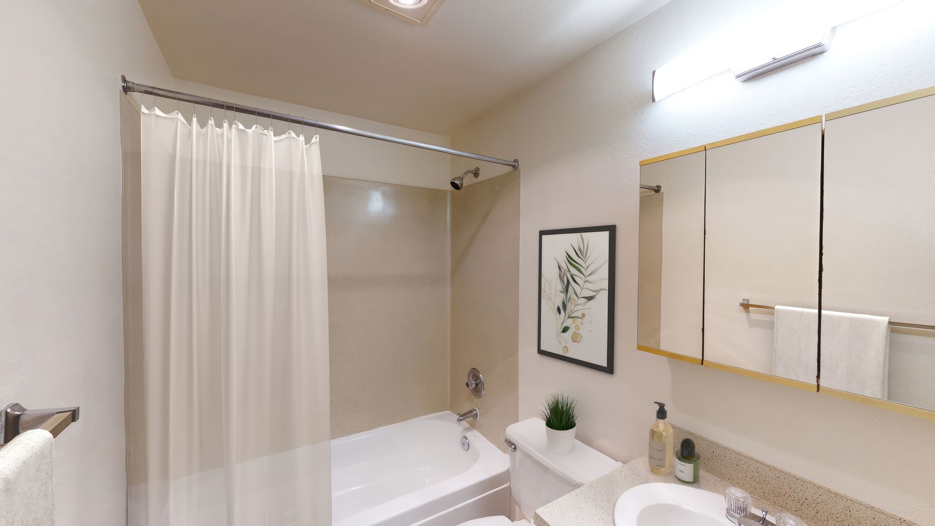A bathroom with a tub , toilet , sink and mirror.
