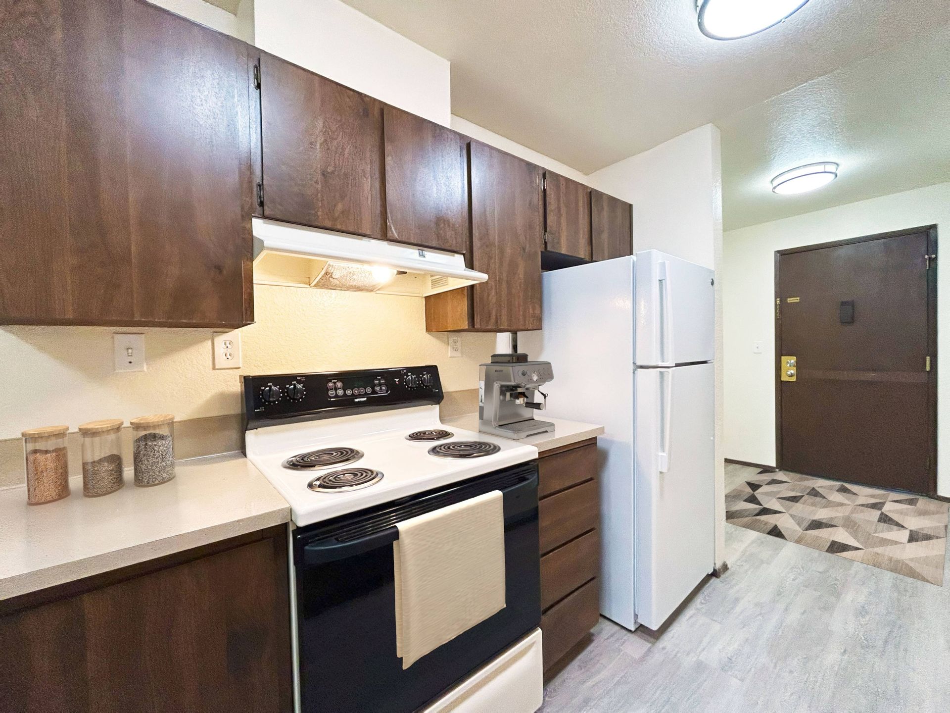 A kitchen with a stove , refrigerator , and microwave.