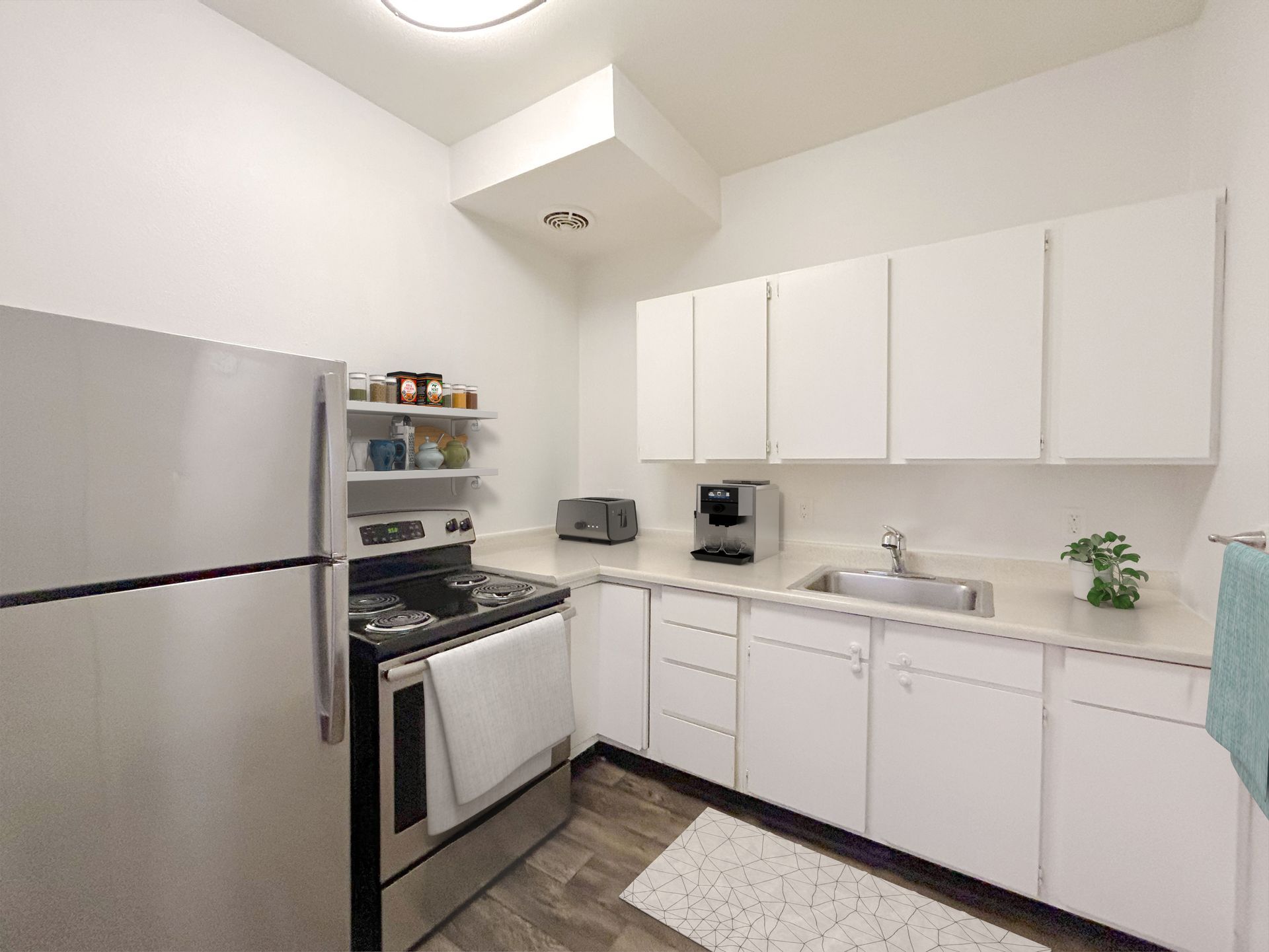 A kitchen with white cabinets , stainless steel appliances , a refrigerator , stove and sink.