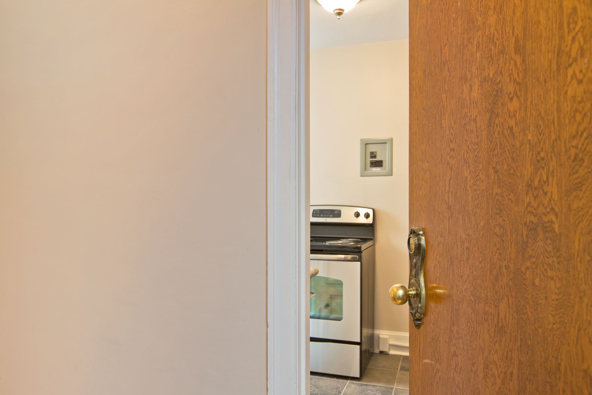 A wooden door is open to a kitchen with a stove.