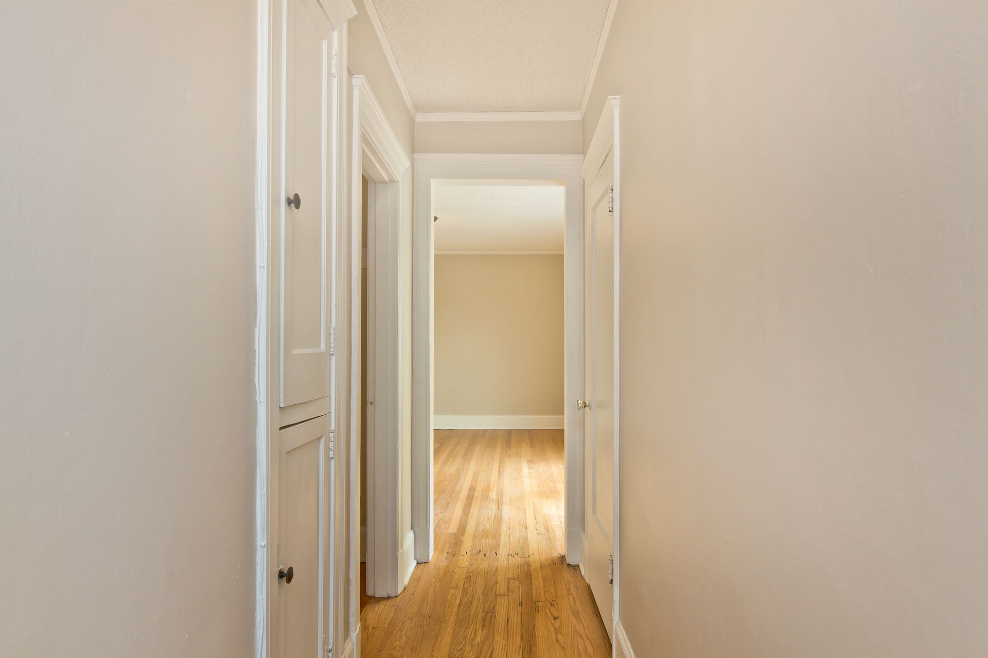 An empty hallway with hardwood floors and white walls in a house.