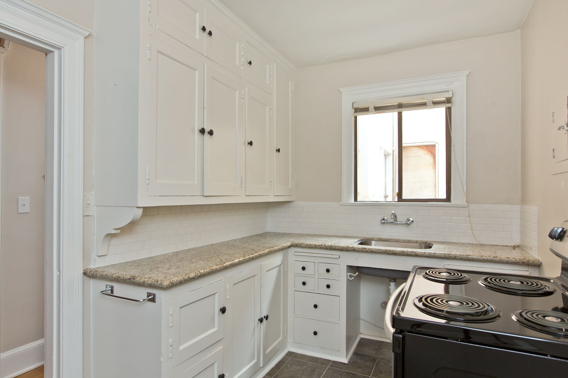 A kitchen with white cabinets and a black stove