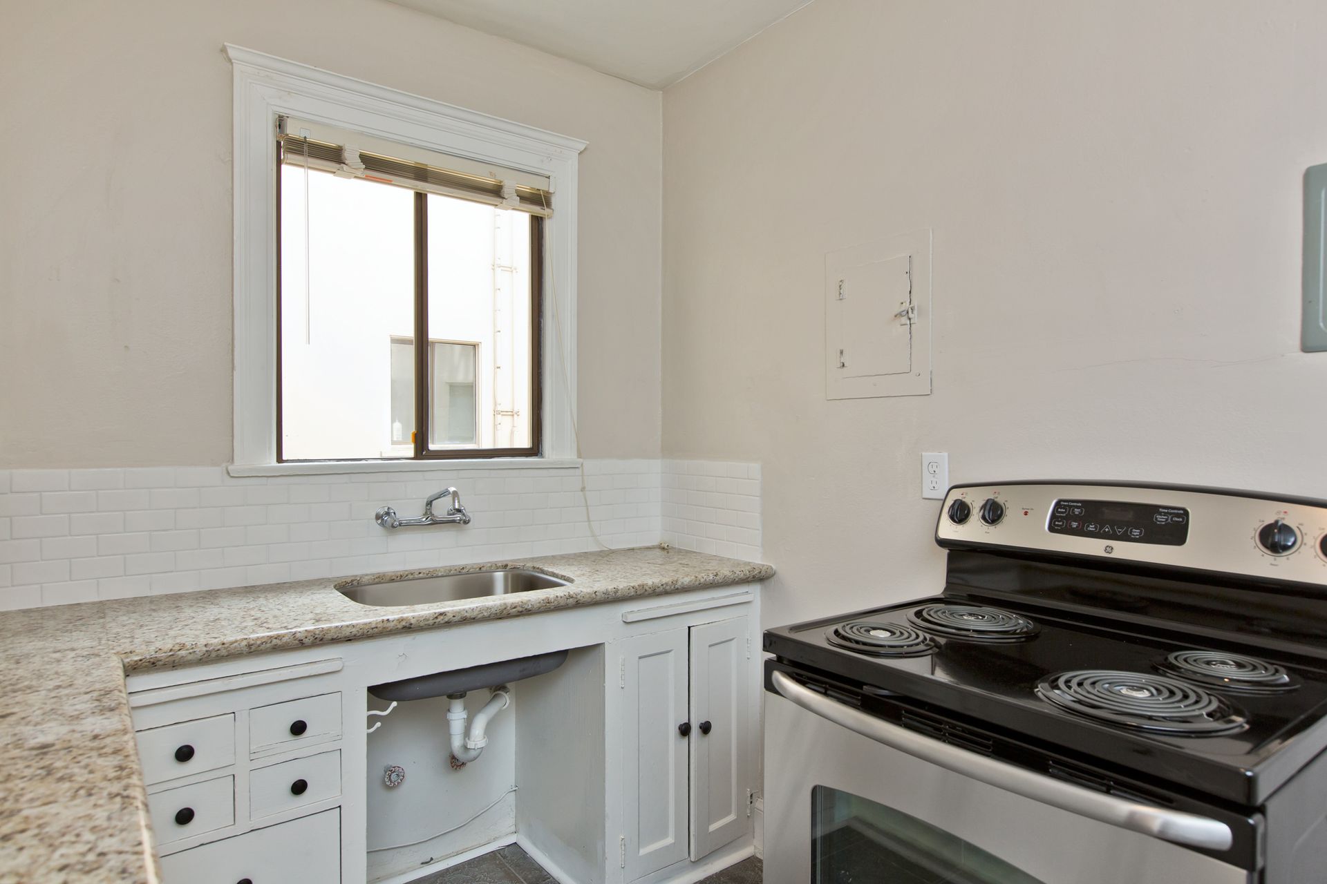 A kitchen with a stove , sink , and window