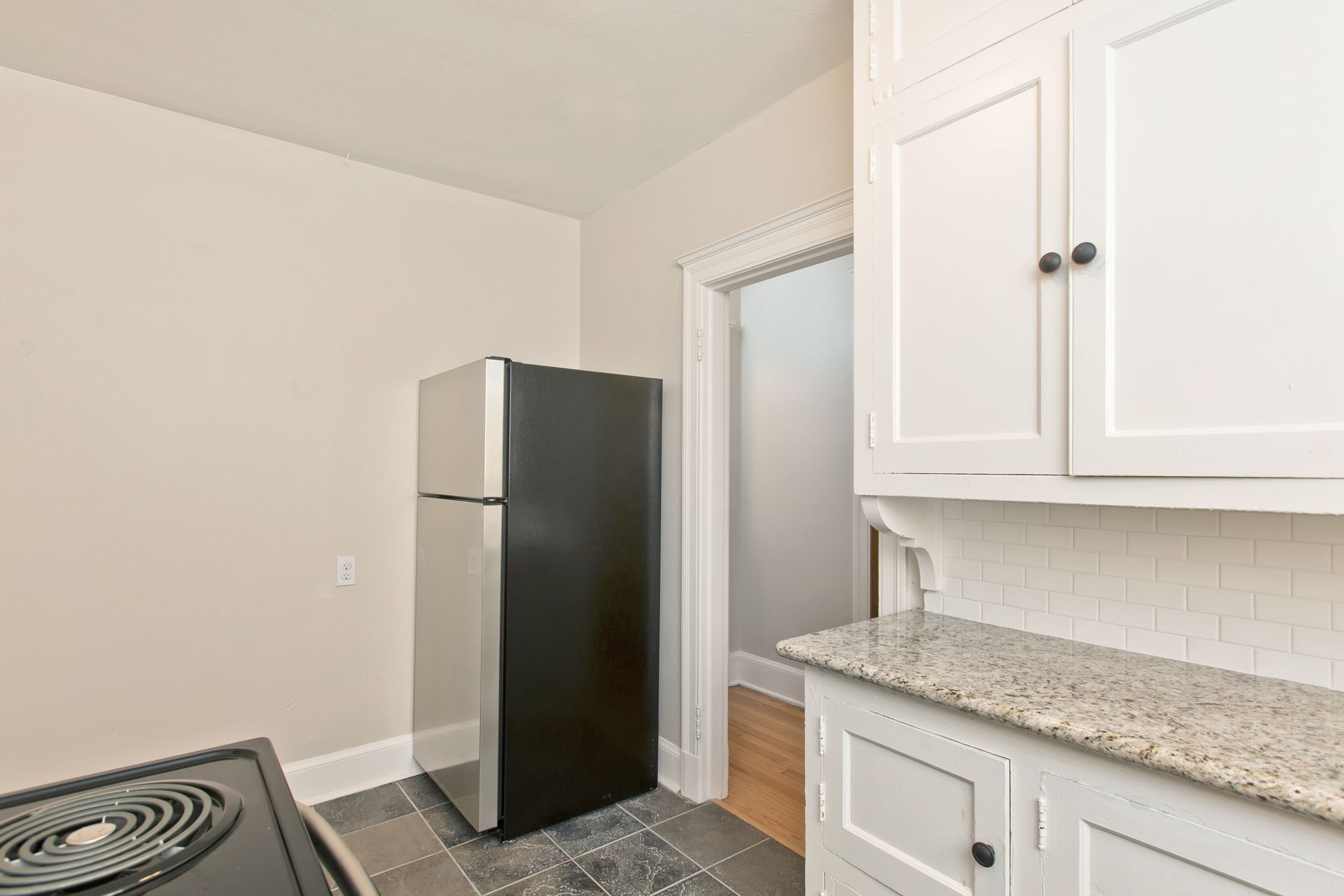 A kitchen with a black refrigerator and white cabinets.