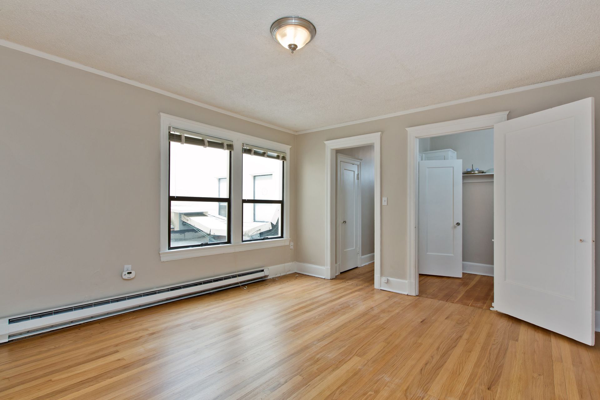 An empty room with hardwood floors and two windows
