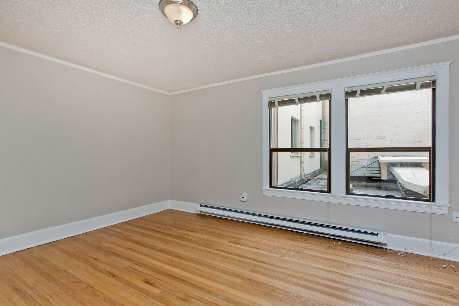 An empty room with hardwood floors and two windows