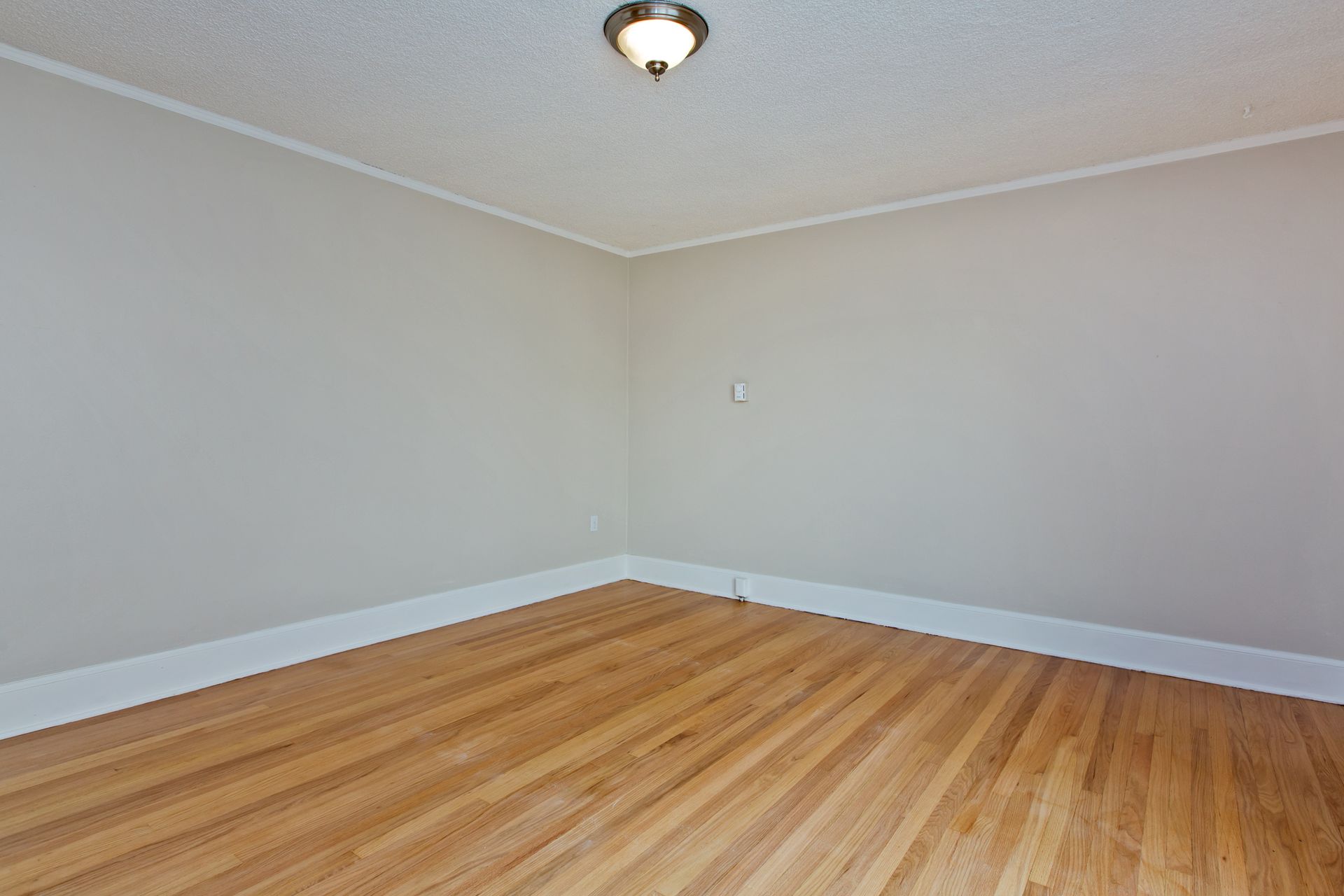 An empty room with hardwood floors and white trim