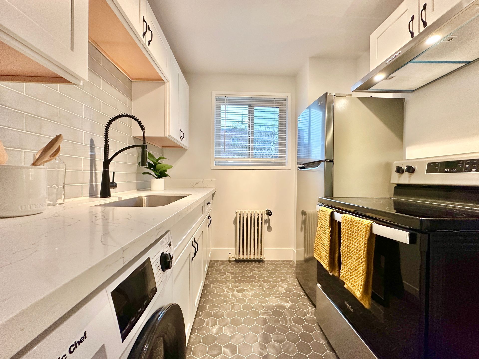 A kitchen with a washing machine , stove , refrigerator and sink.