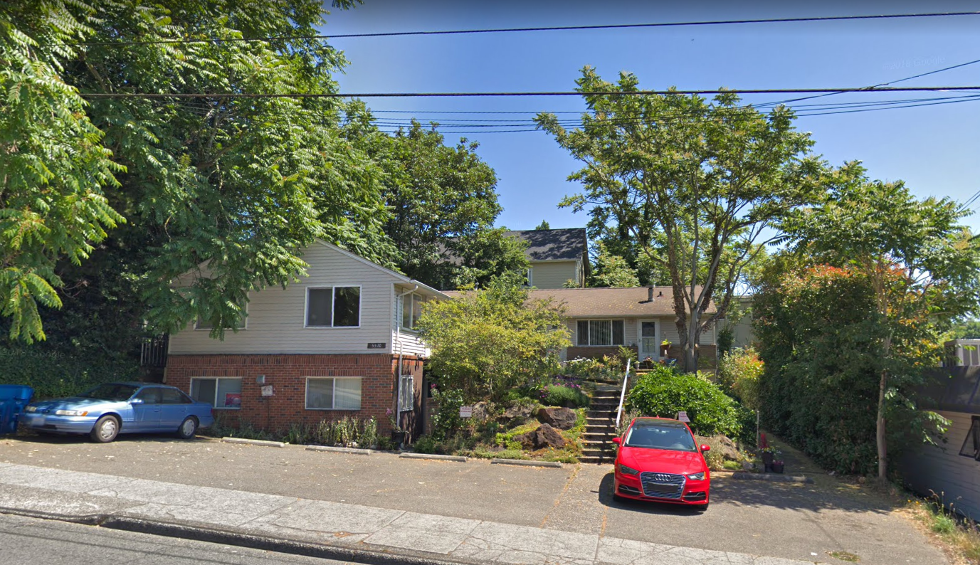 A red car is parked in front of a house.