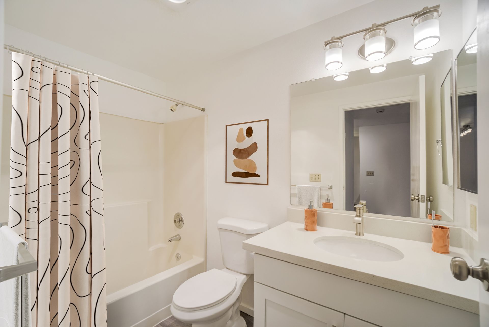 A bathroom with a toilet , sink , shower and mirror.