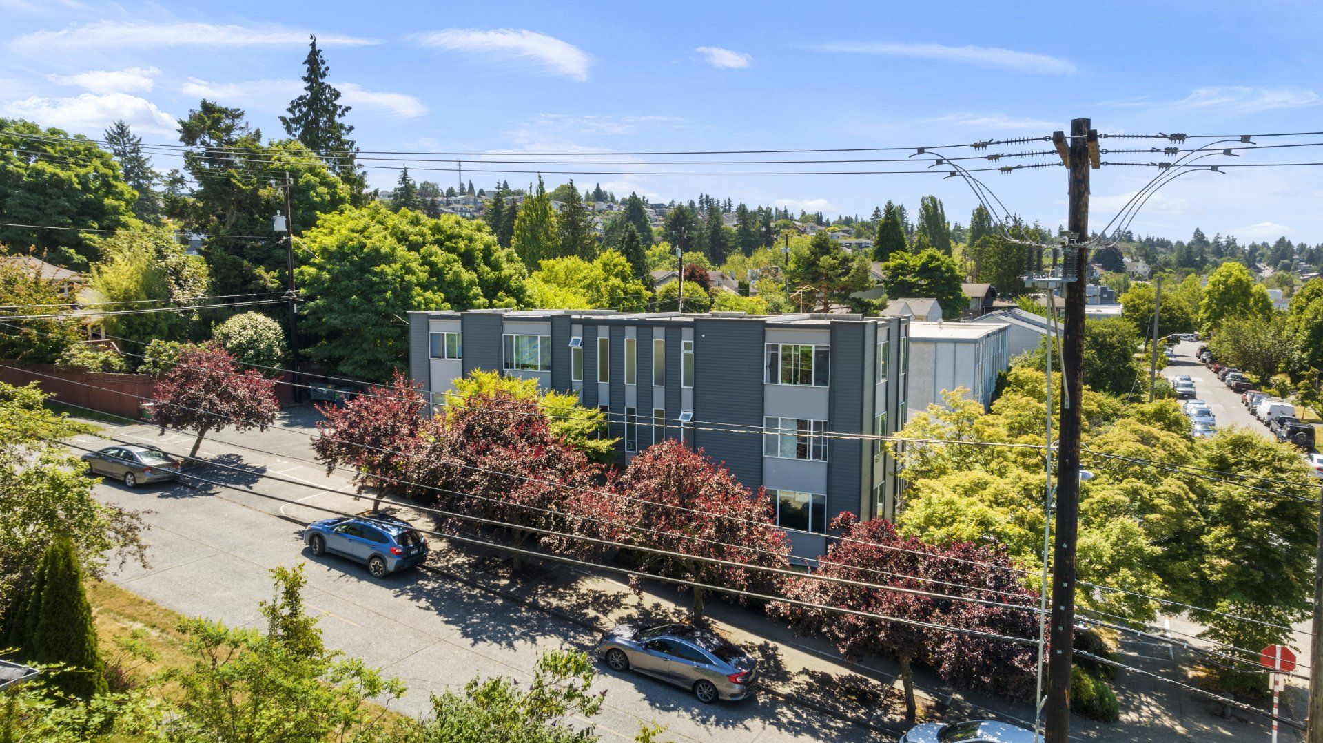 An aerial view of a building with cars parked in front of it surrounded by trees.