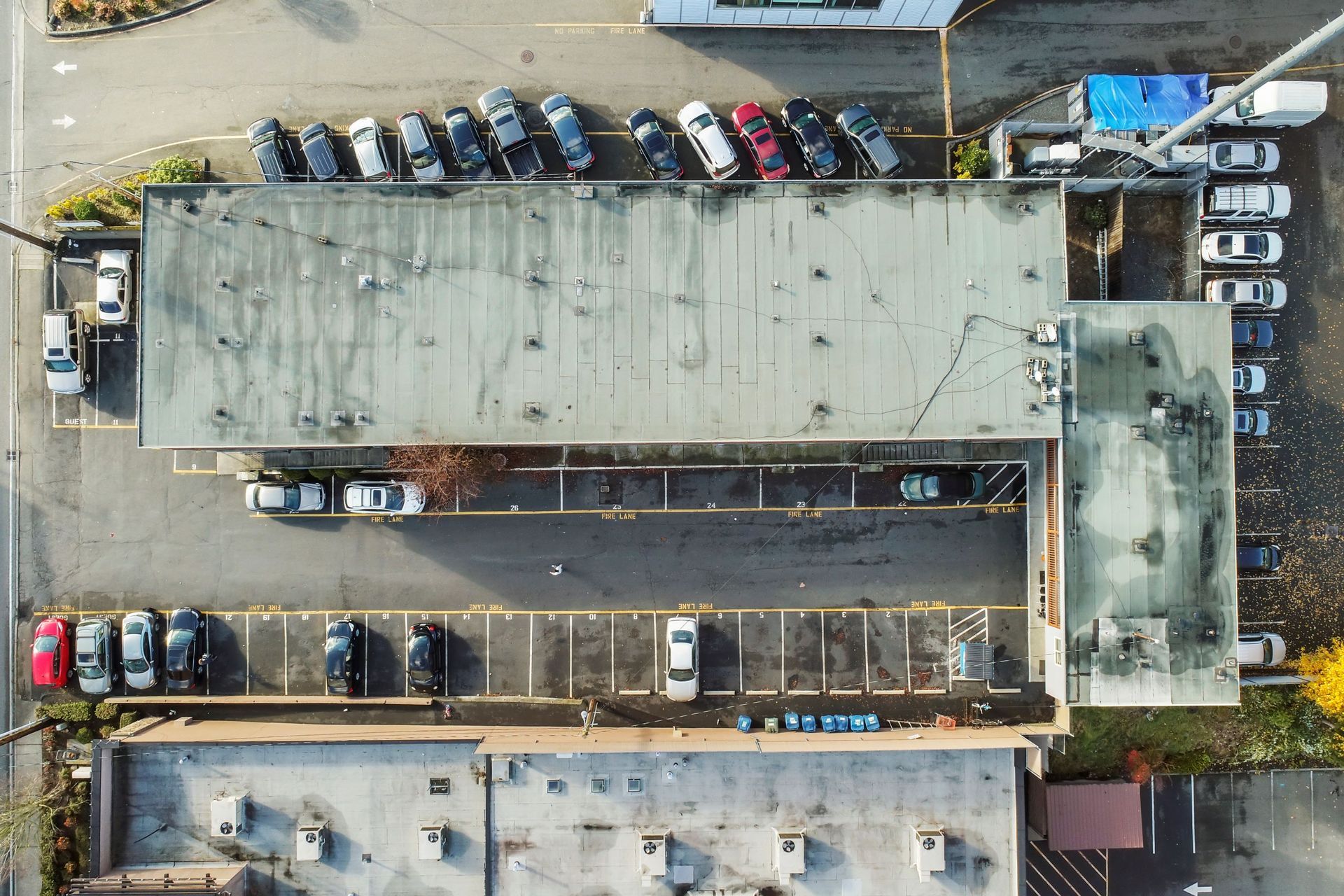 An aerial view of a parking lot with cars parked in front of a building.
