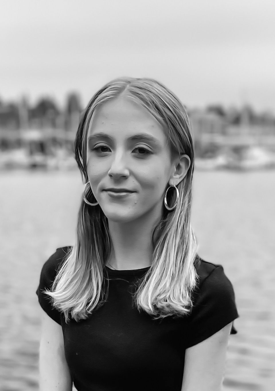 A black and white photo of a young girl wearing a black shirt and earrings.