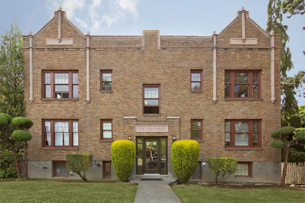A large brick apartment building with a lush green lawn in front of it