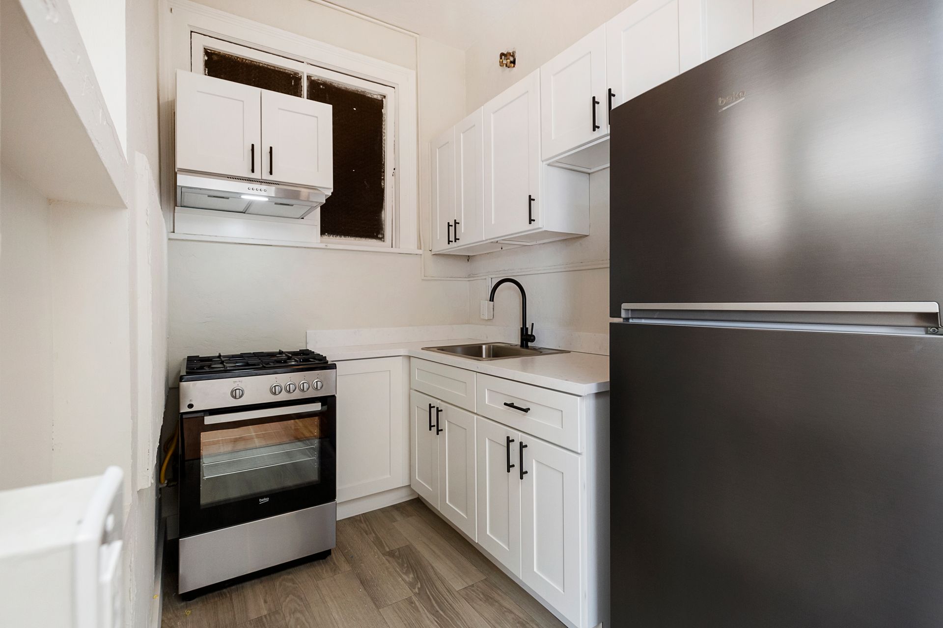 A kitchen with white cabinets and a black refrigerator