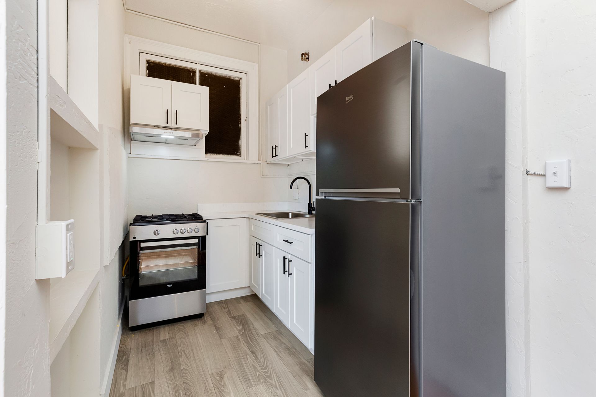 A kitchen with a black refrigerator , stove , and sink.