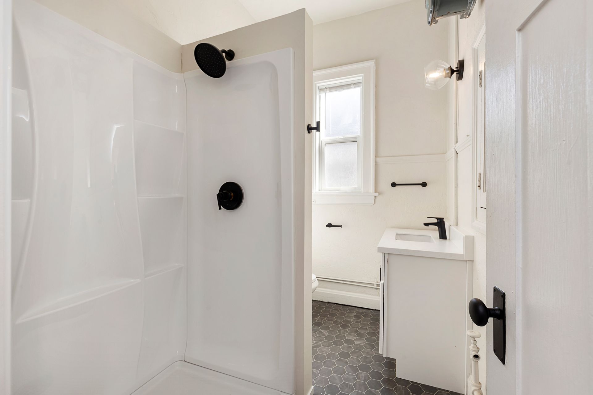 A bathroom with a shower , sink , and window.