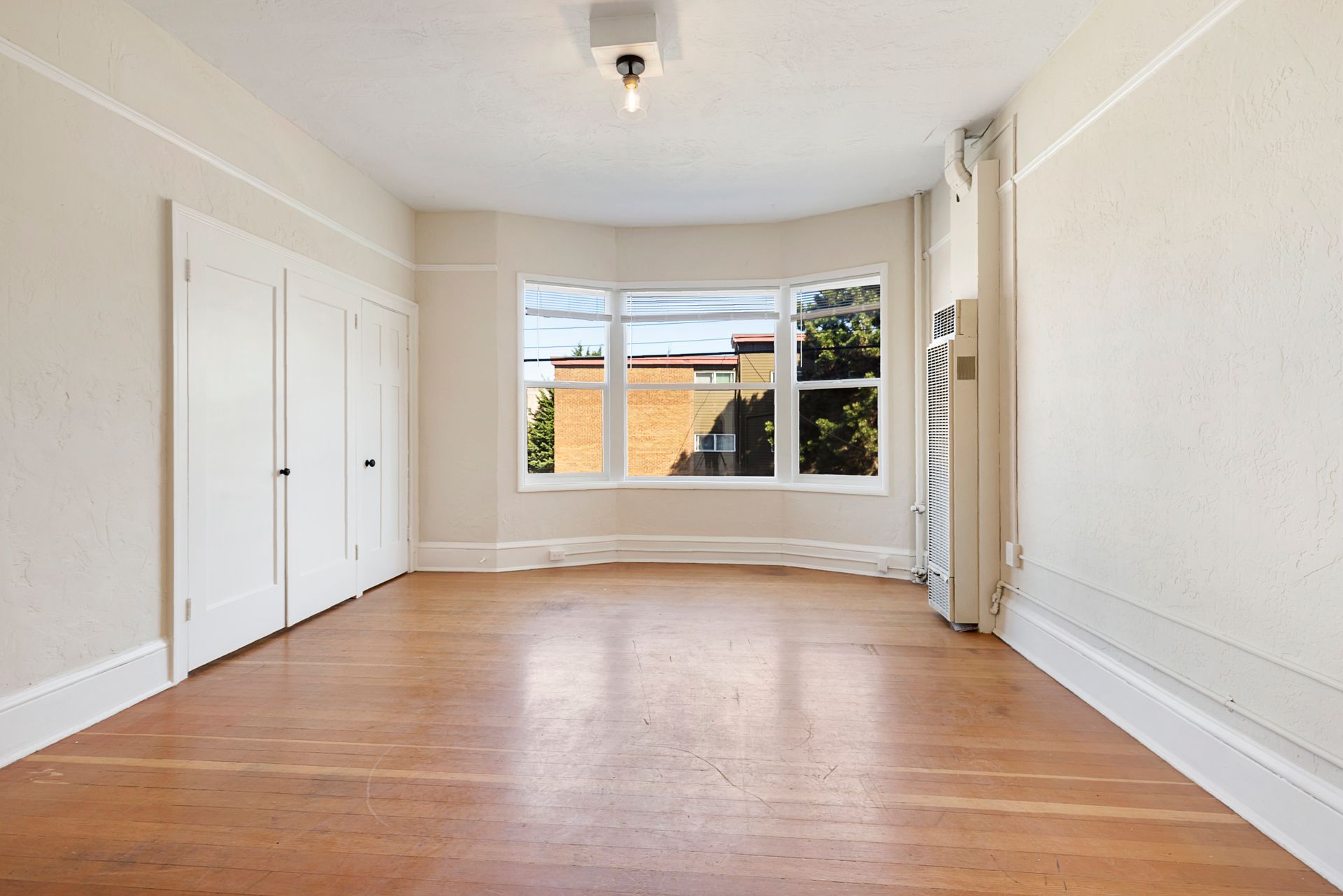 An empty room with hardwood floors and a large window