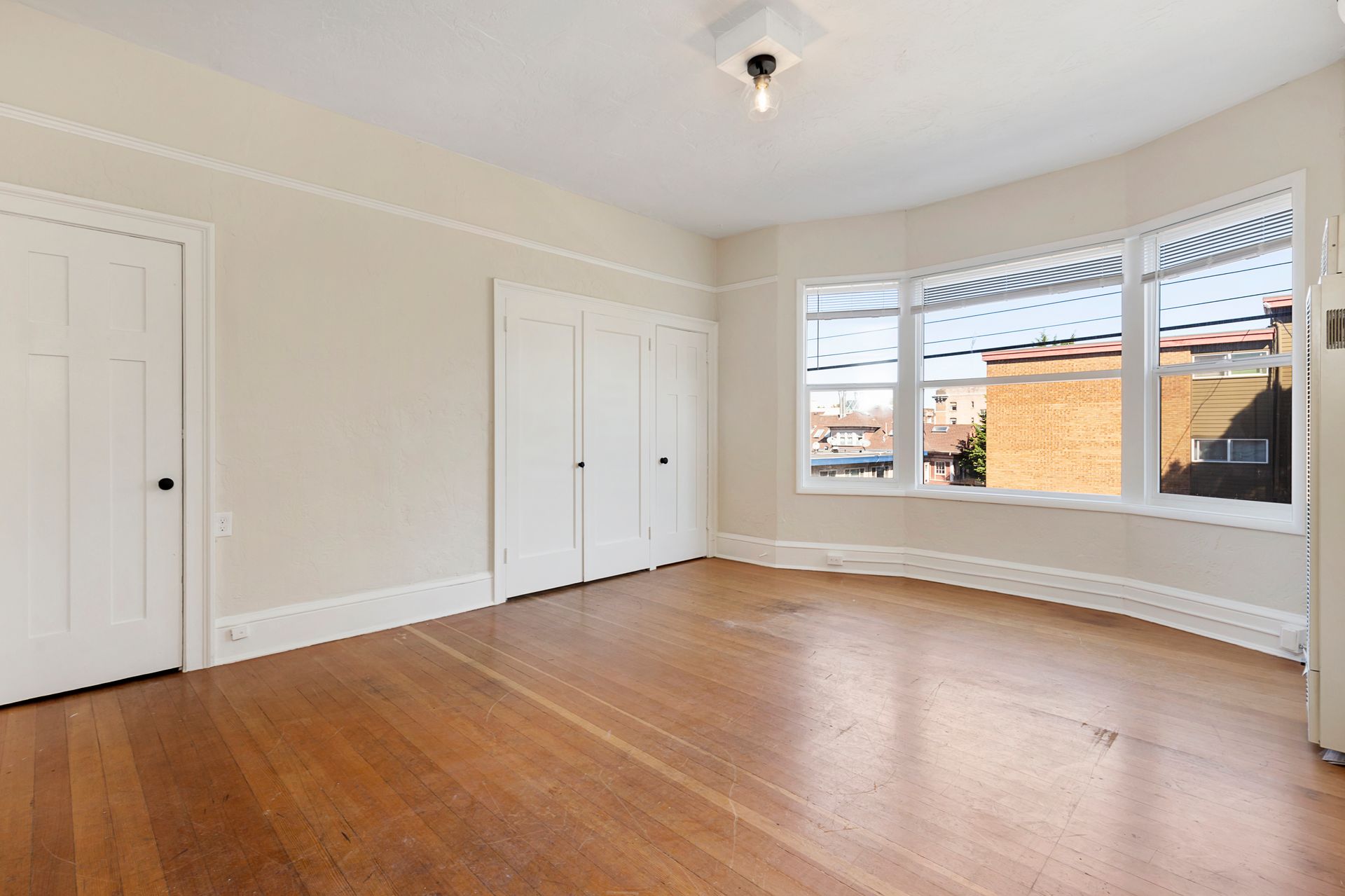 An empty living room with hardwood floors and white walls.