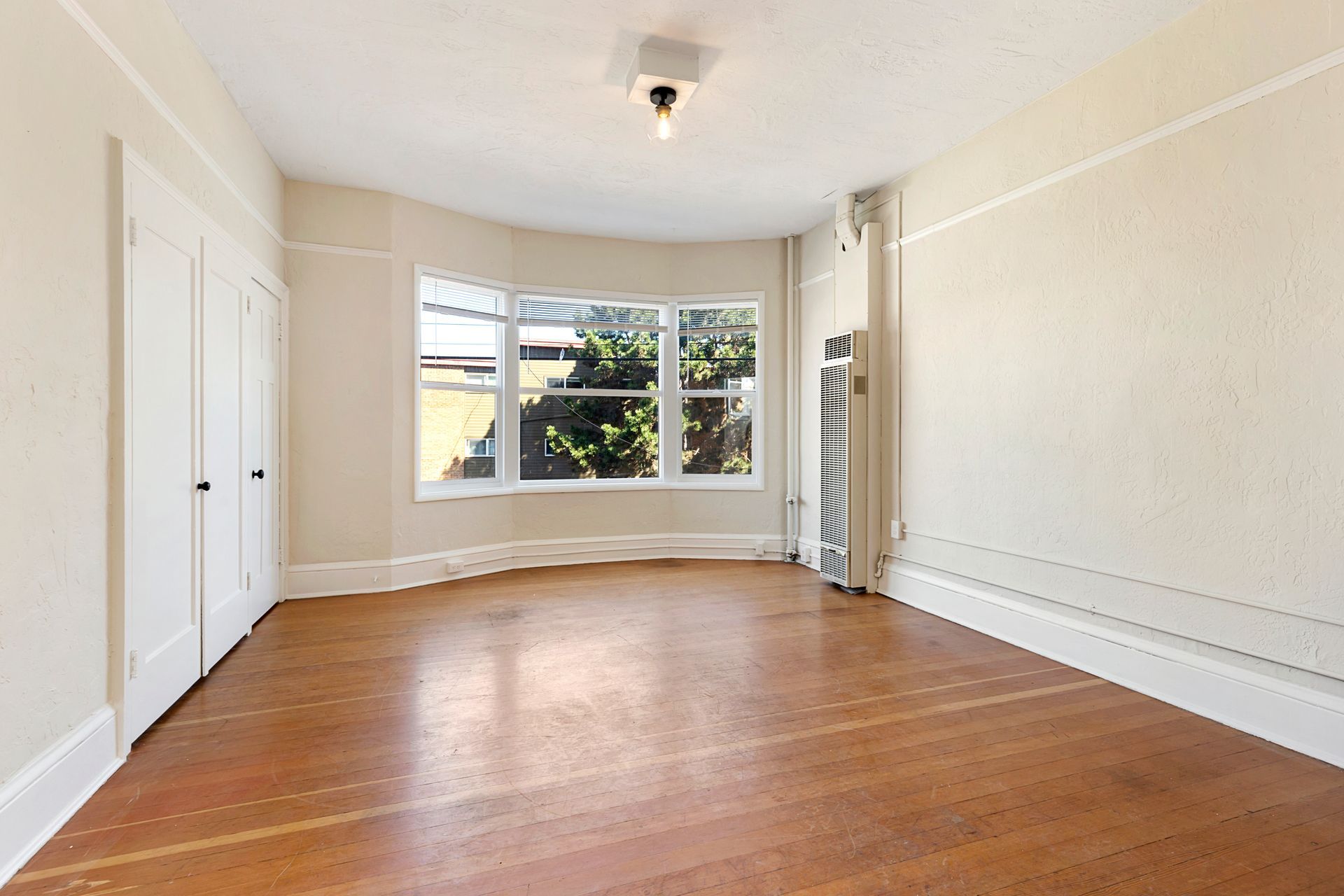 An empty room with hardwood floors and white walls