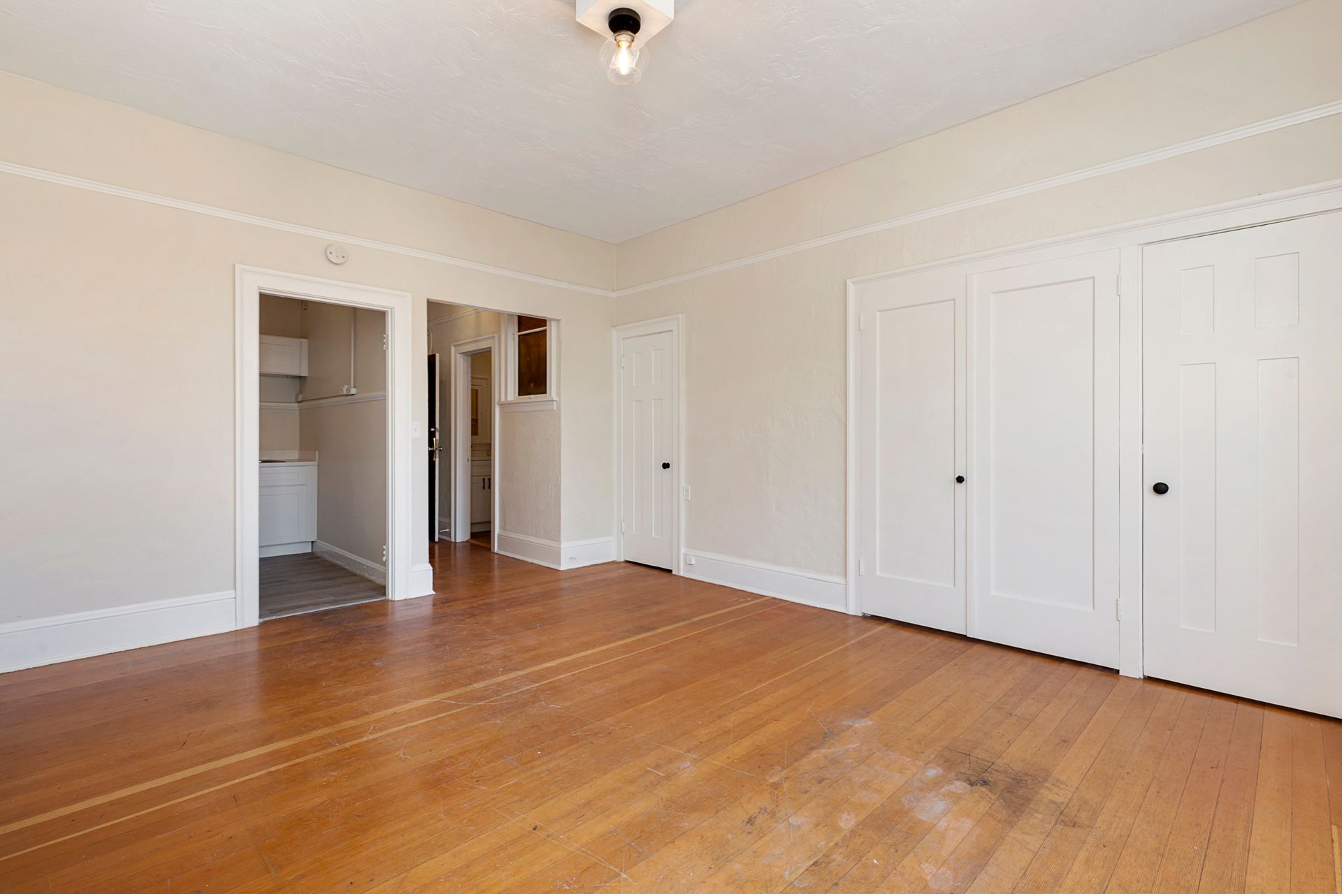 An empty living room with hardwood floors and white walls.