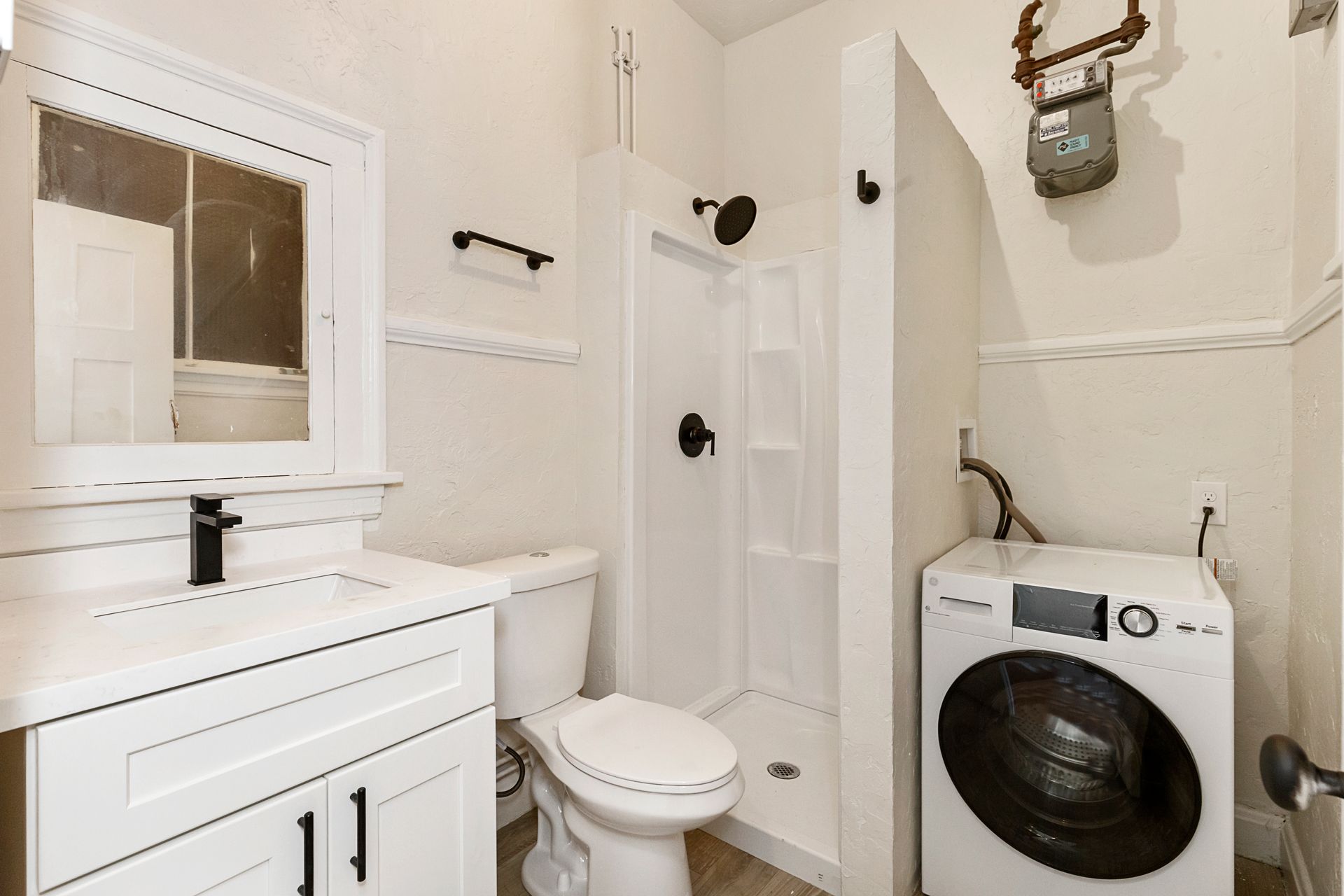 A bathroom with a toilet , sink , and washing machine.