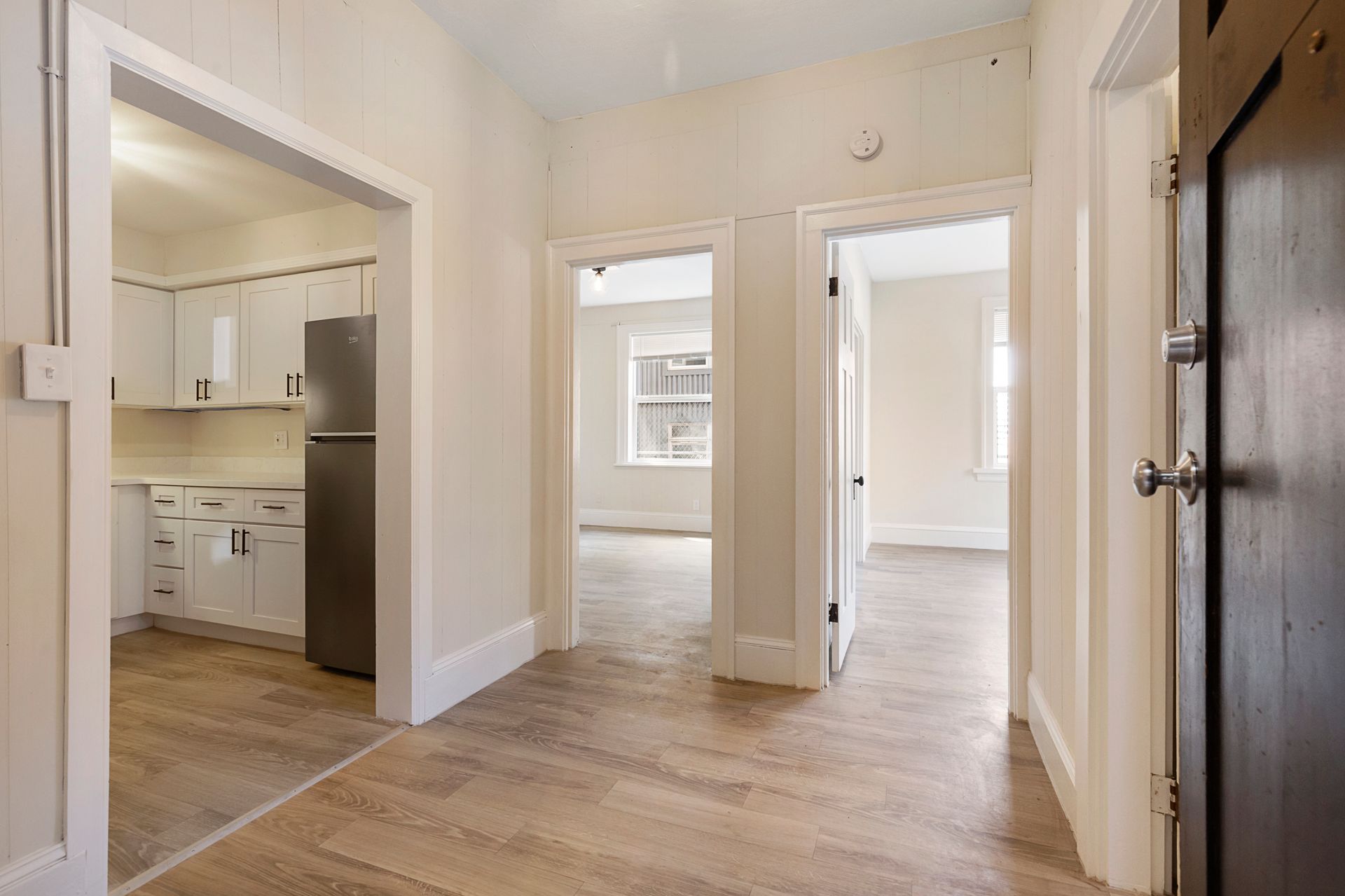 A hallway leading to a kitchen and a living room in a house.