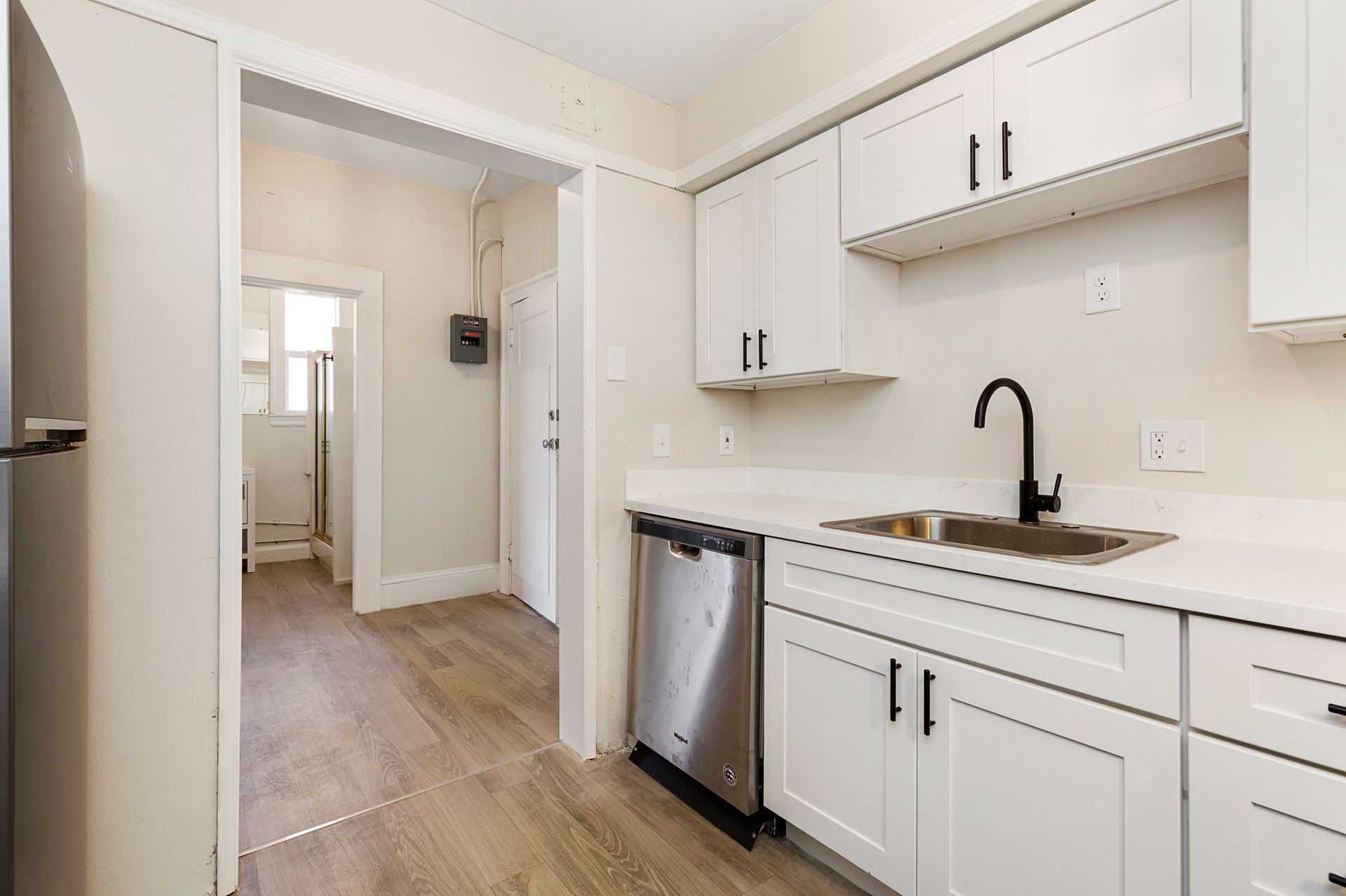A kitchen with white cabinets , stainless steel appliances , a sink , and a refrigerator.