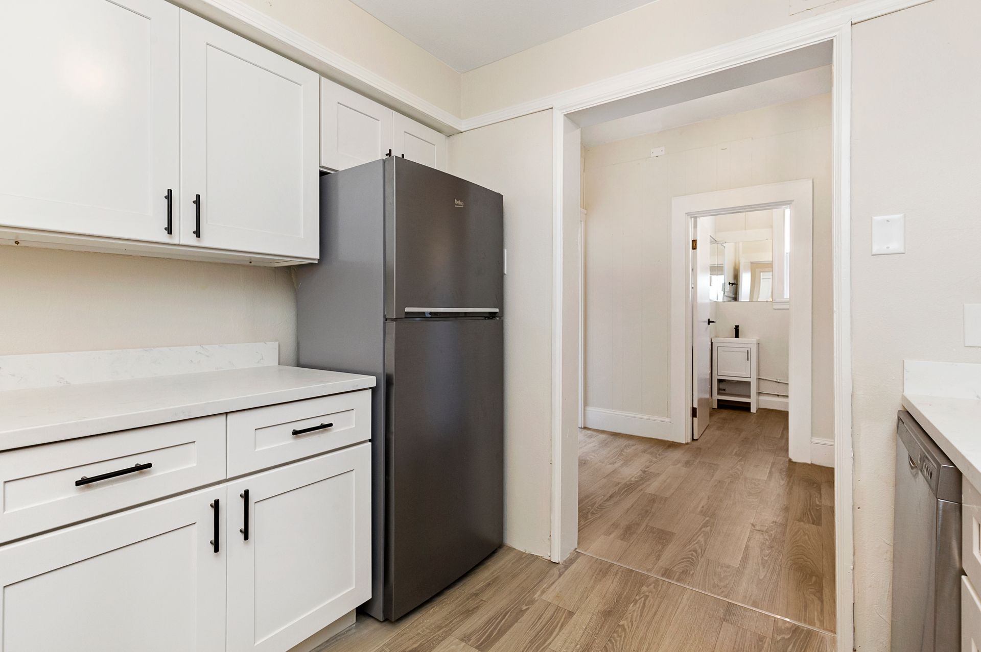A kitchen with white cabinets and a black refrigerator