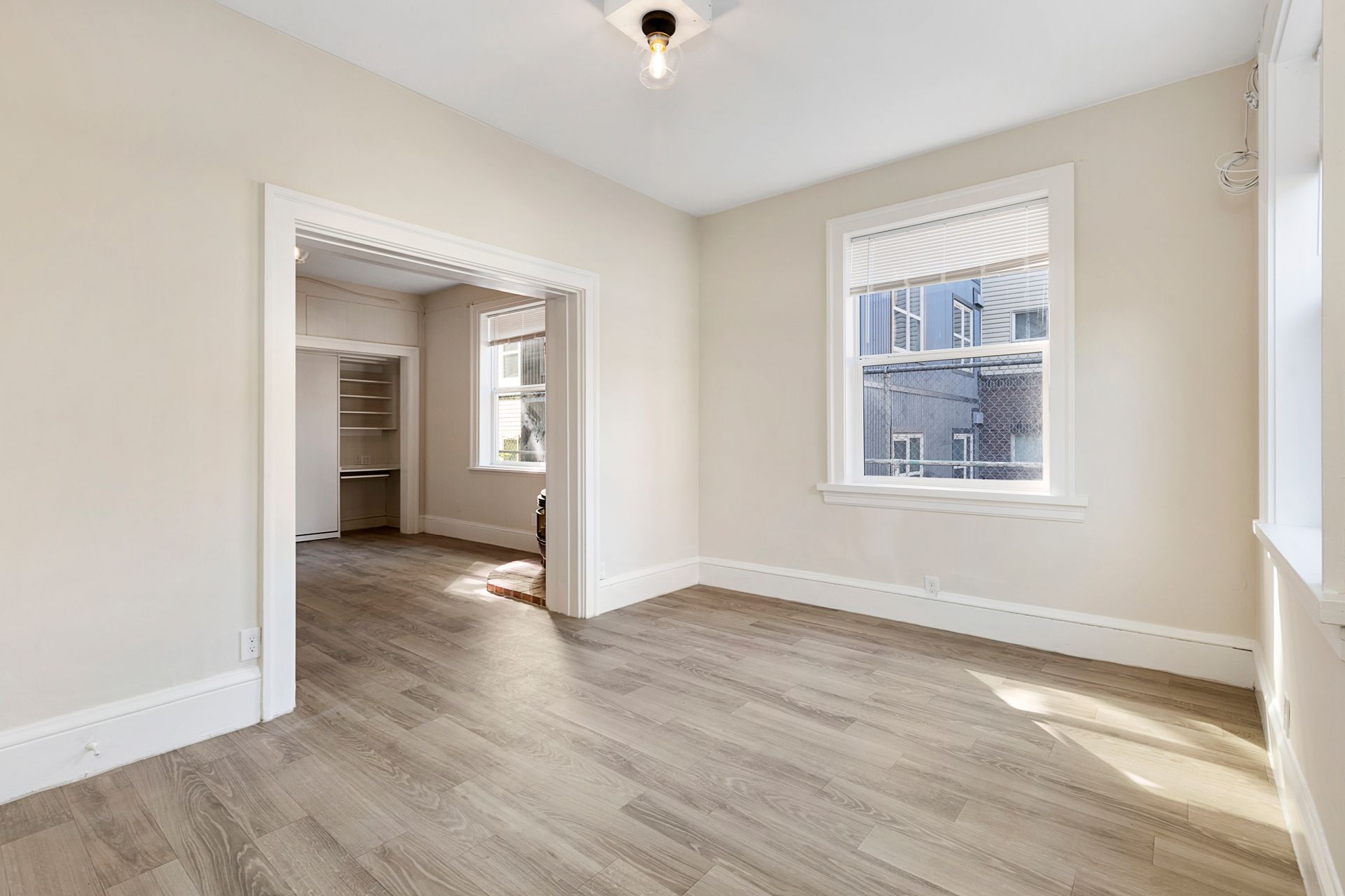 An empty room with hardwood floors and two windows.