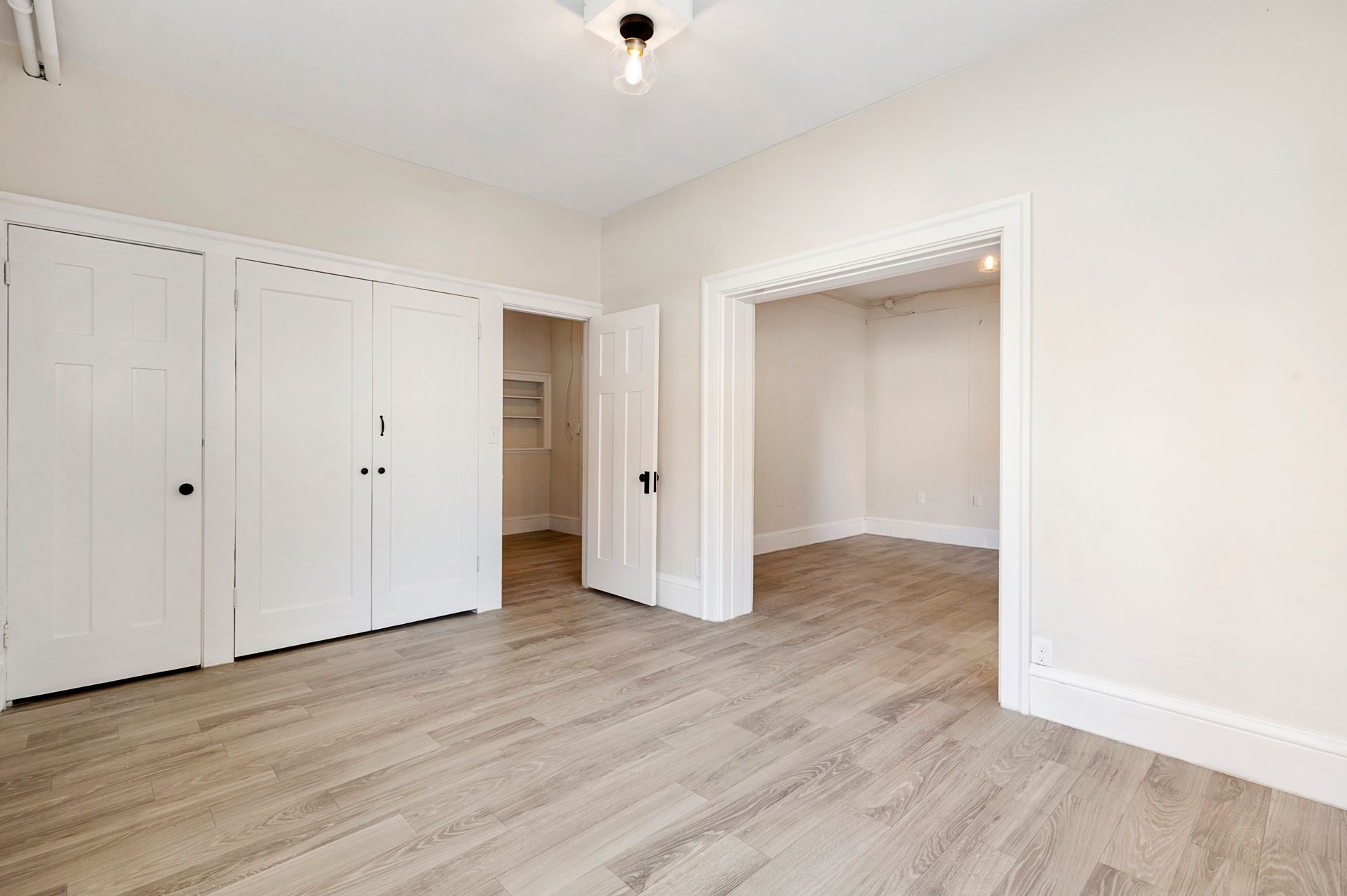 A large empty room with hardwood floors and white walls.