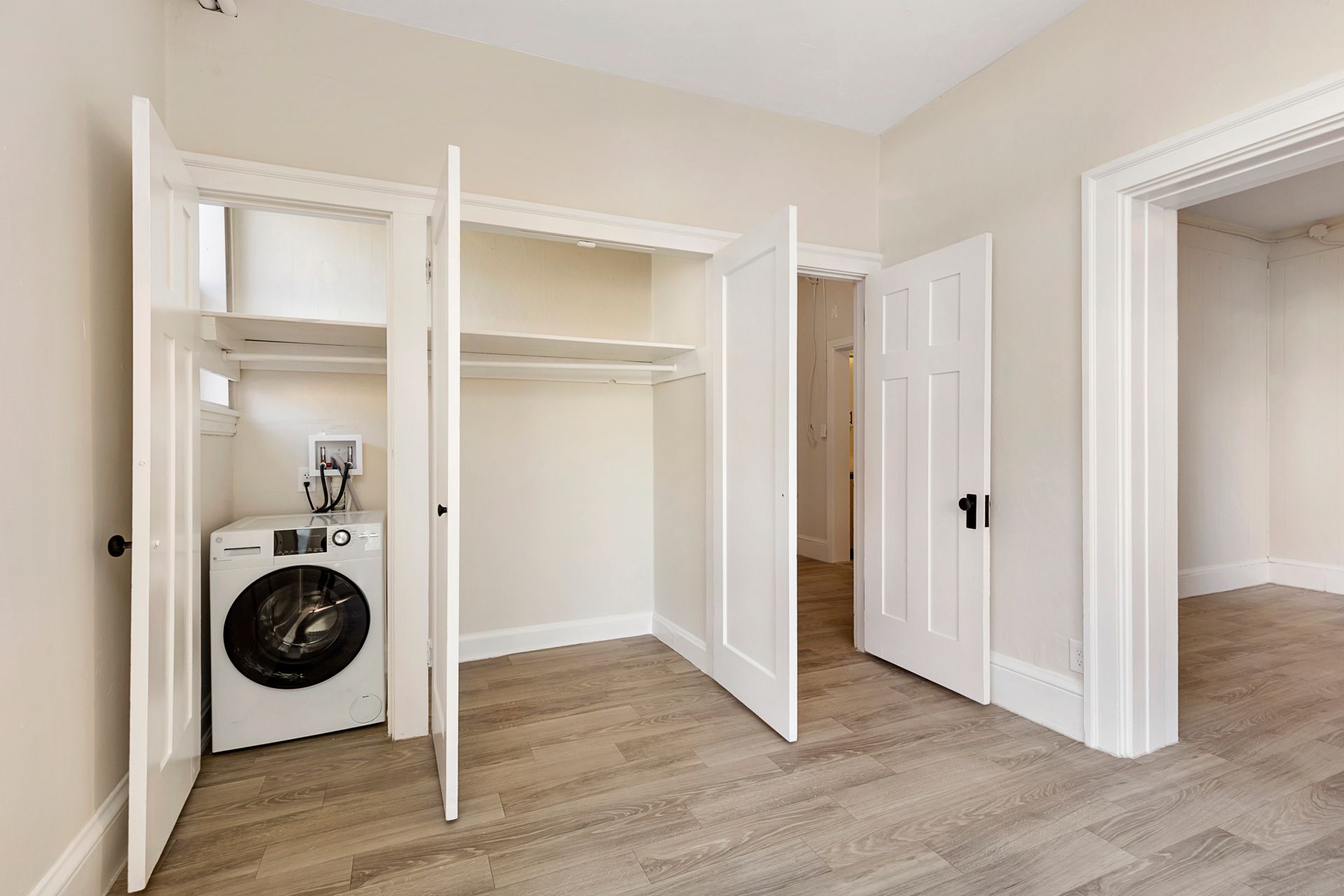 An empty room with a washer and dryer in a closet.