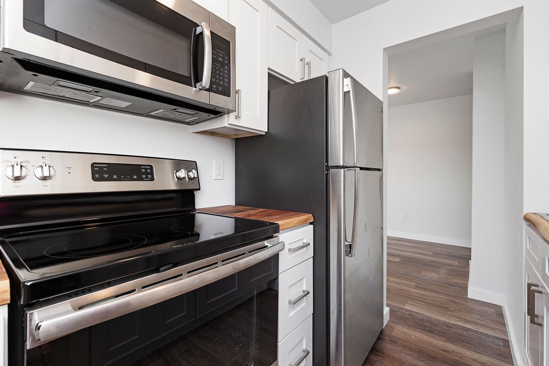 A kitchen with a stove , refrigerator and microwave.
