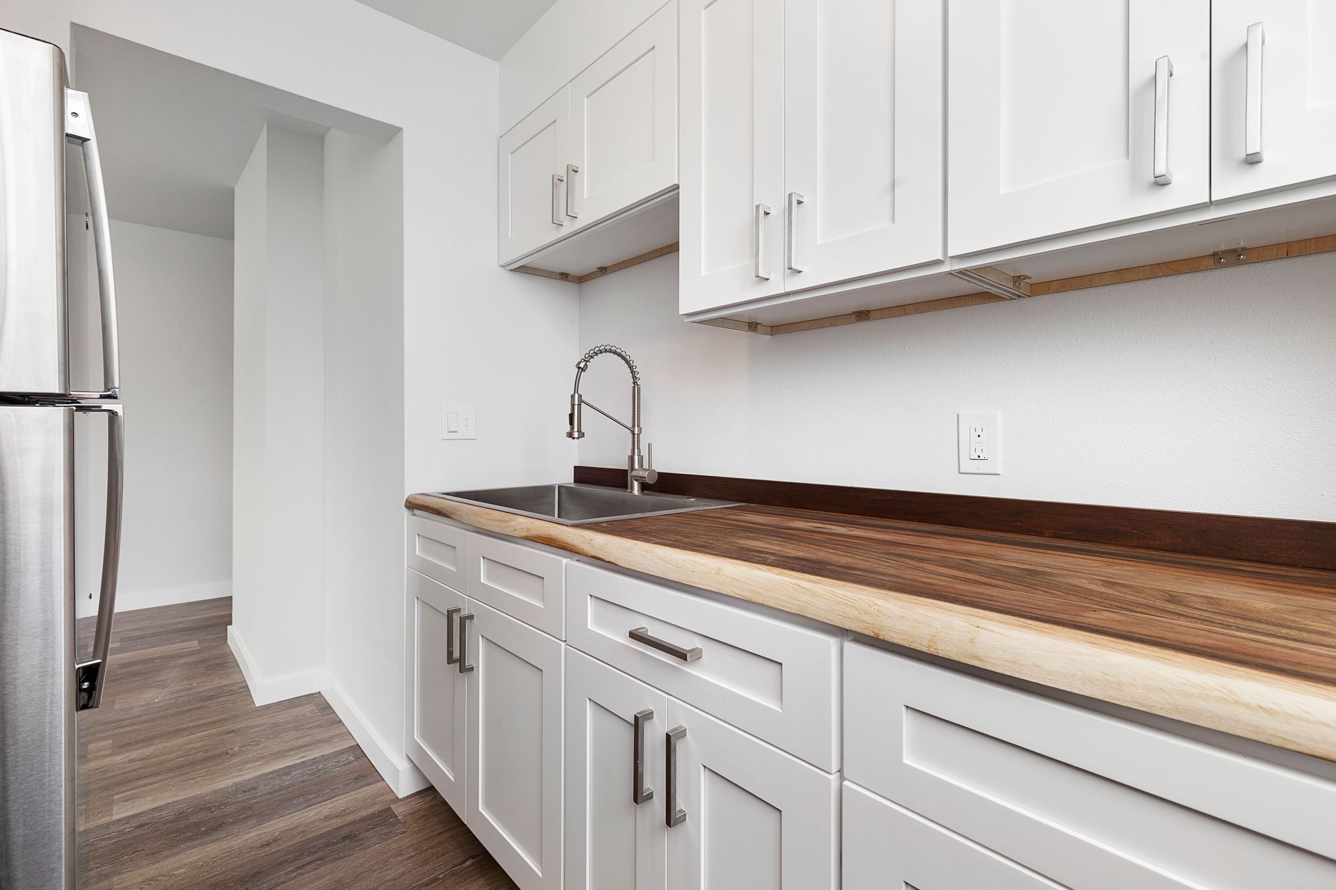 A kitchen with white cabinets and a stainless steel refrigerator