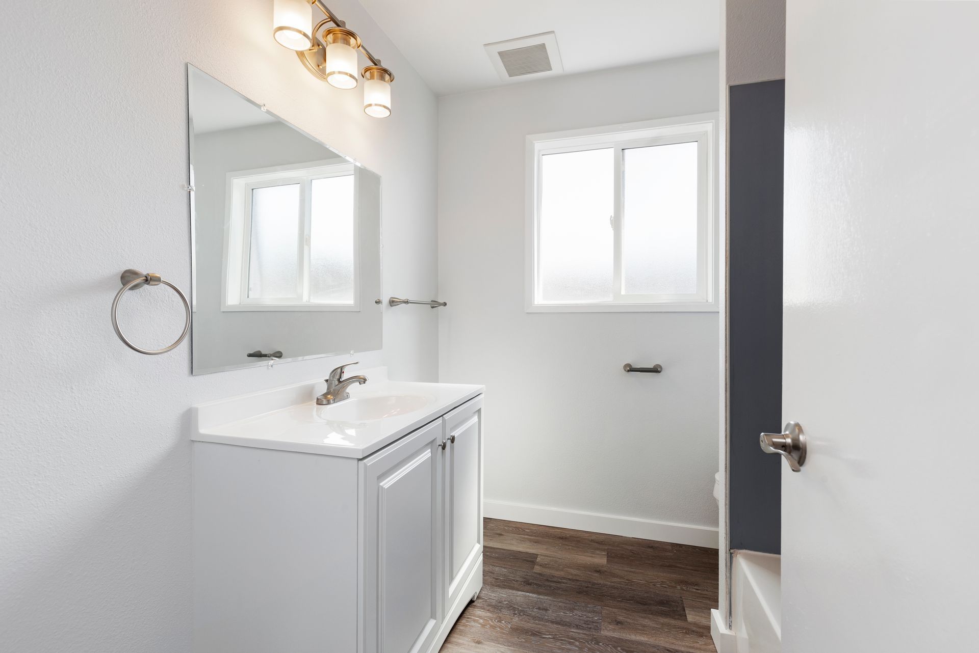 A bathroom with a sink , mirror and window.