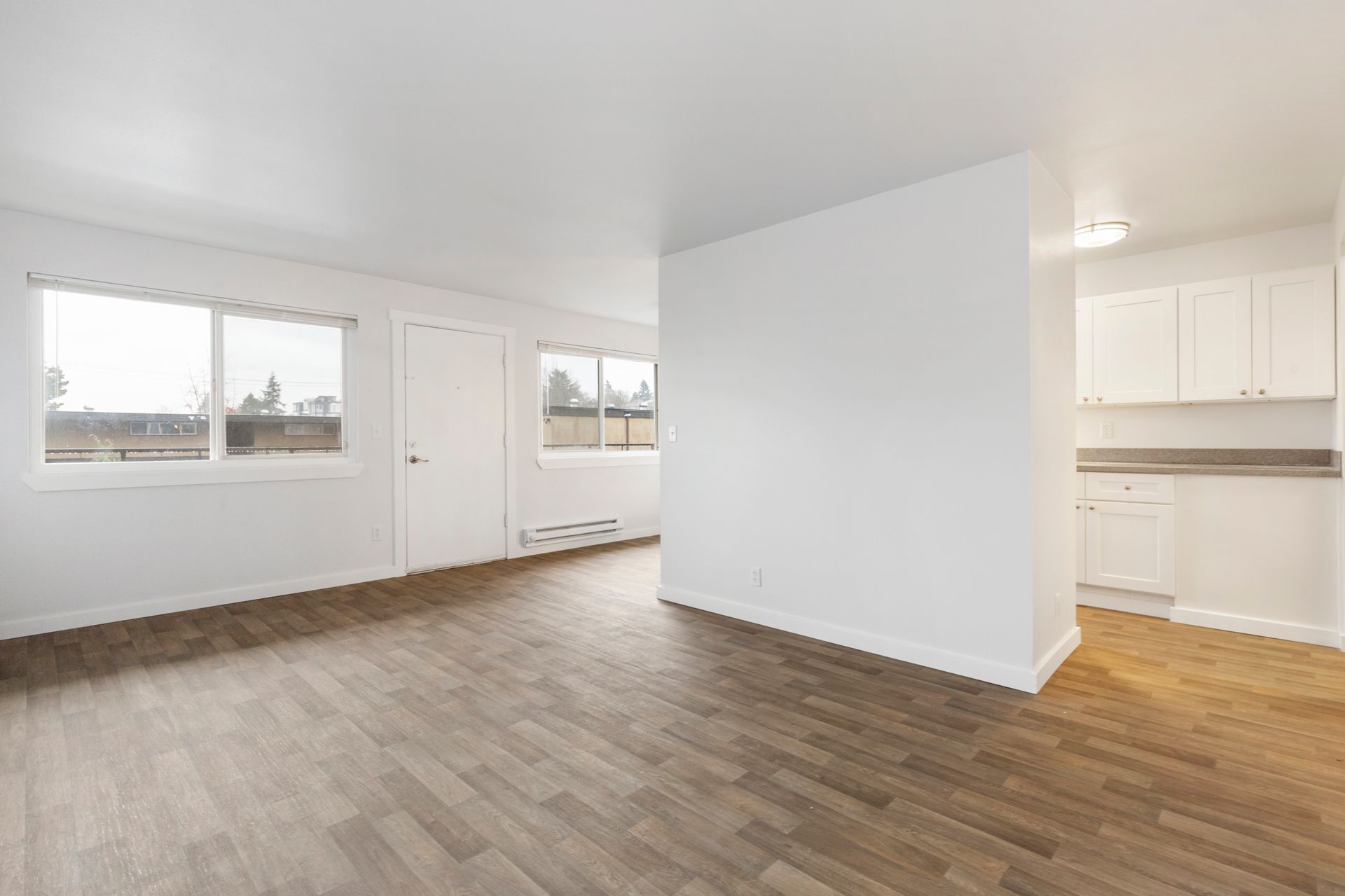 An empty apartment with hardwood floors and white walls.