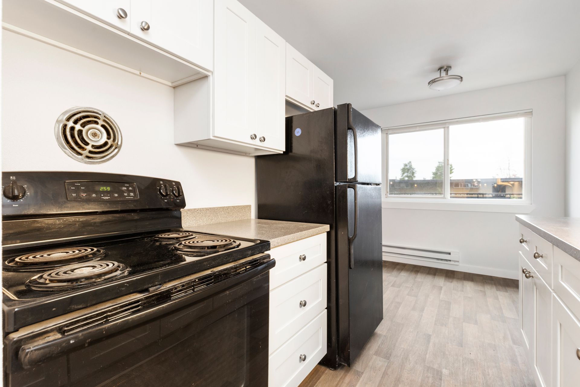 A kitchen with a black stove , black refrigerator and white cabinets.